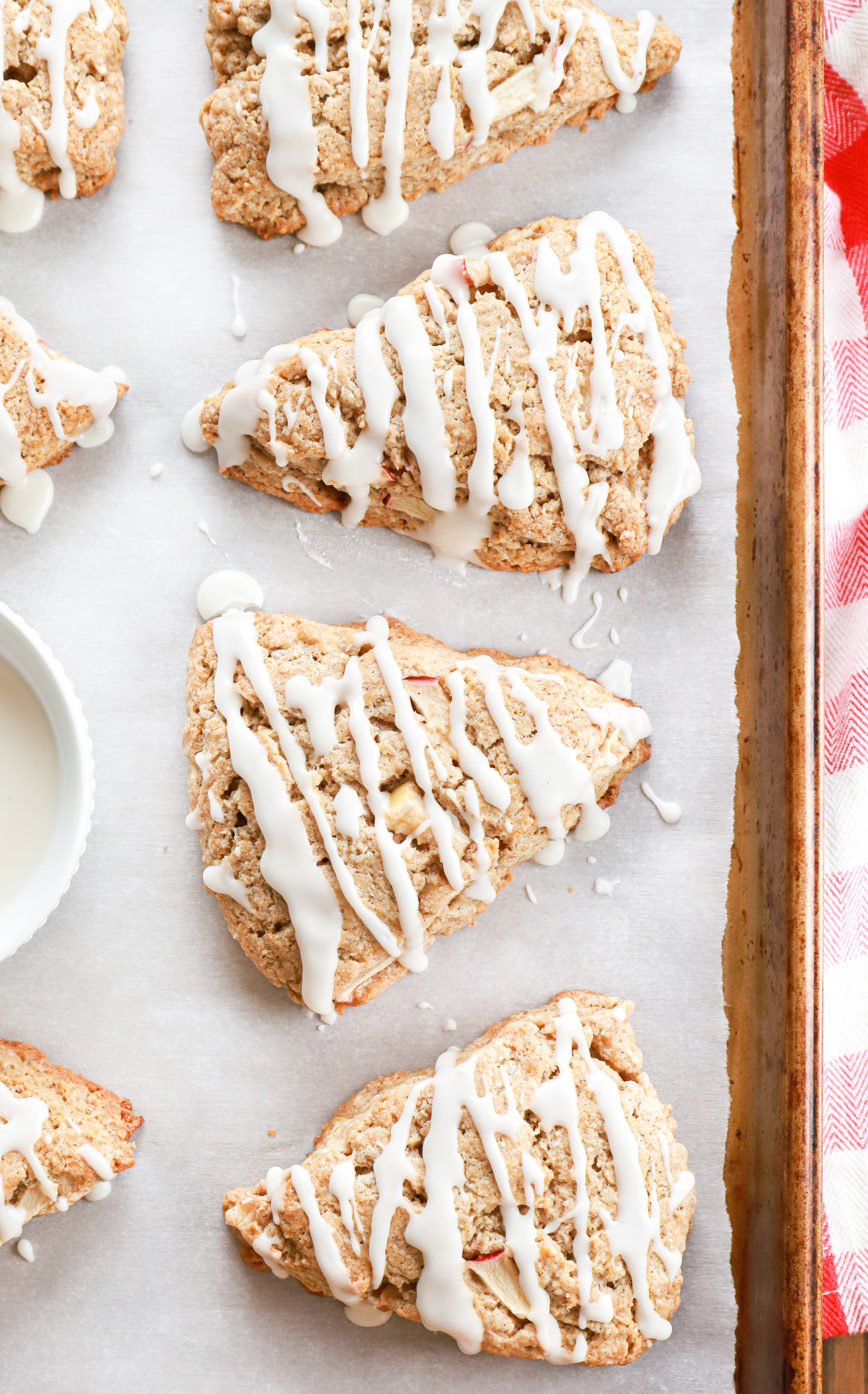 Up close overhead view of a few apple cinnamon scones on a parchment paper lined baking sheet.