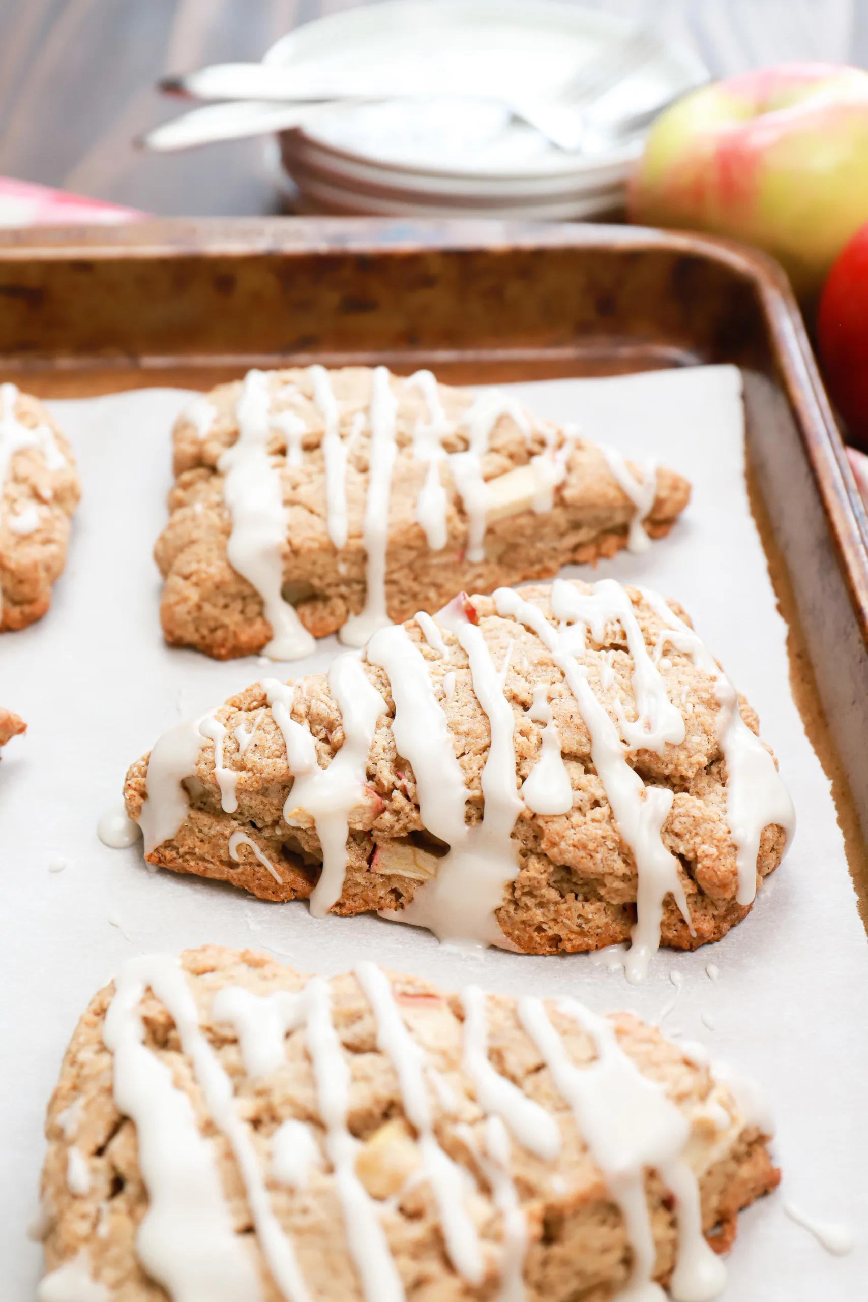 Up close side view of an apple cinnamon scone on a parchment paper lined baking sheet.