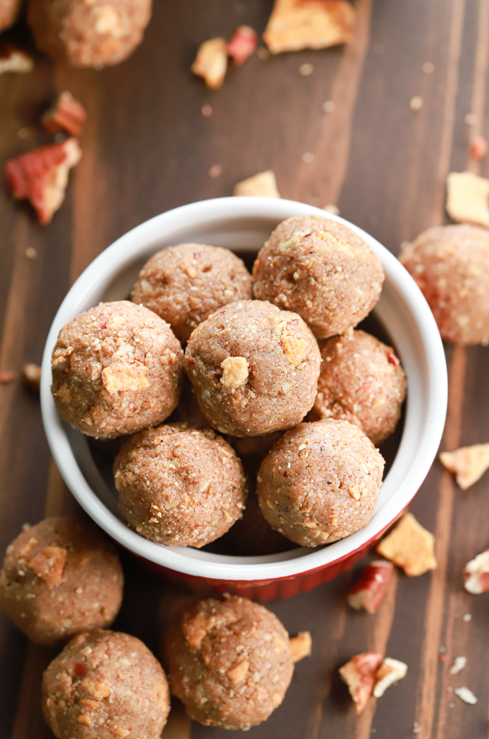 Overhead view of apple pie energy bites in a small red bowl on top of a wooden board.