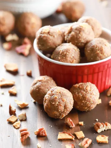 Apple pie protein bites in a small red bowl with a small white bowl full of bites in the background.