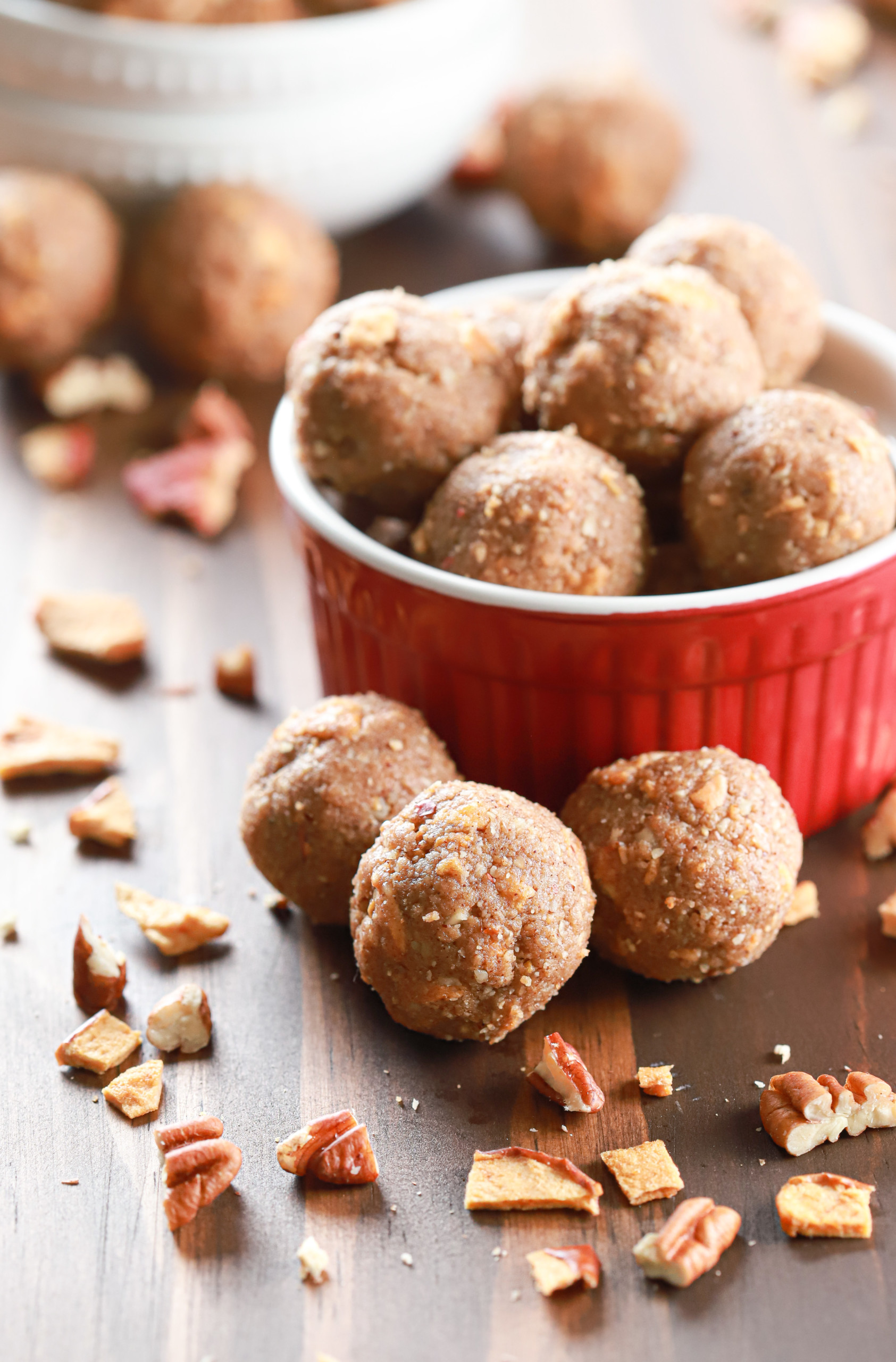 Apple pie protein bites in a small red bowl with a small white bowl full of bites in the background.