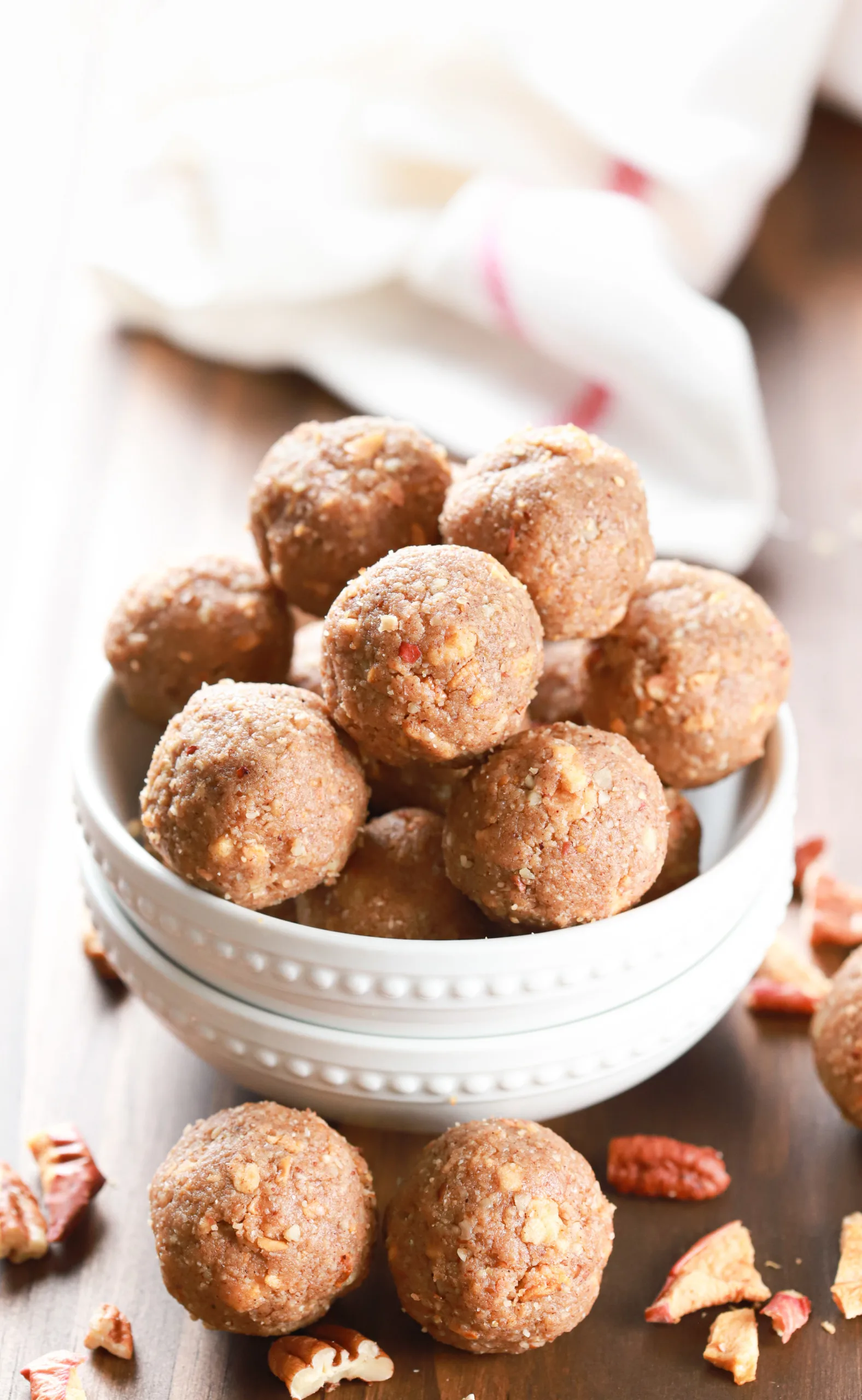 Apple pie energy balls in a small bite bowl with more balls surrounding the bowl.