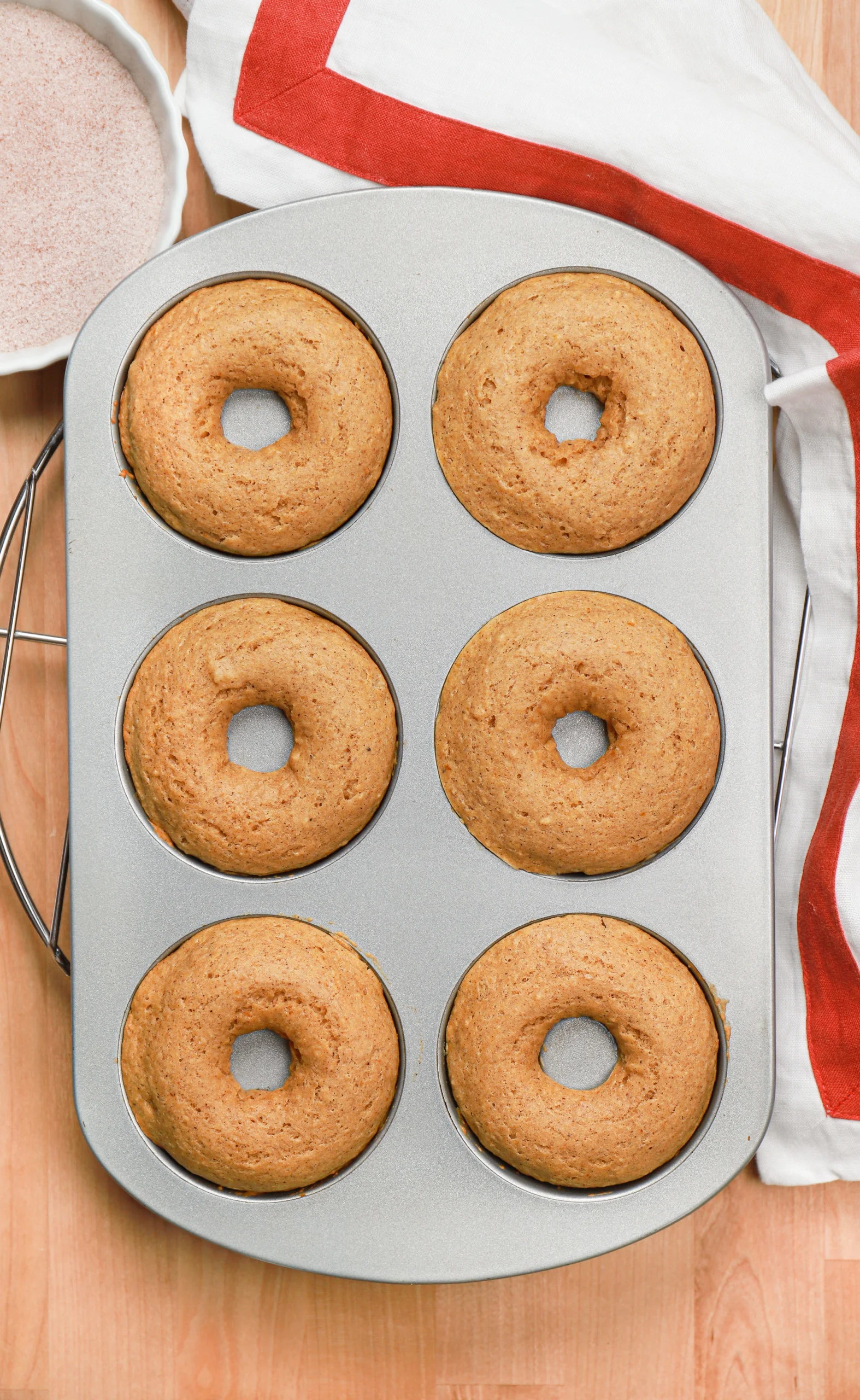 Overhead view of a batch of cinnamon sugar pumpkin donuts in a donut pan before the cinnamon sugar coating.