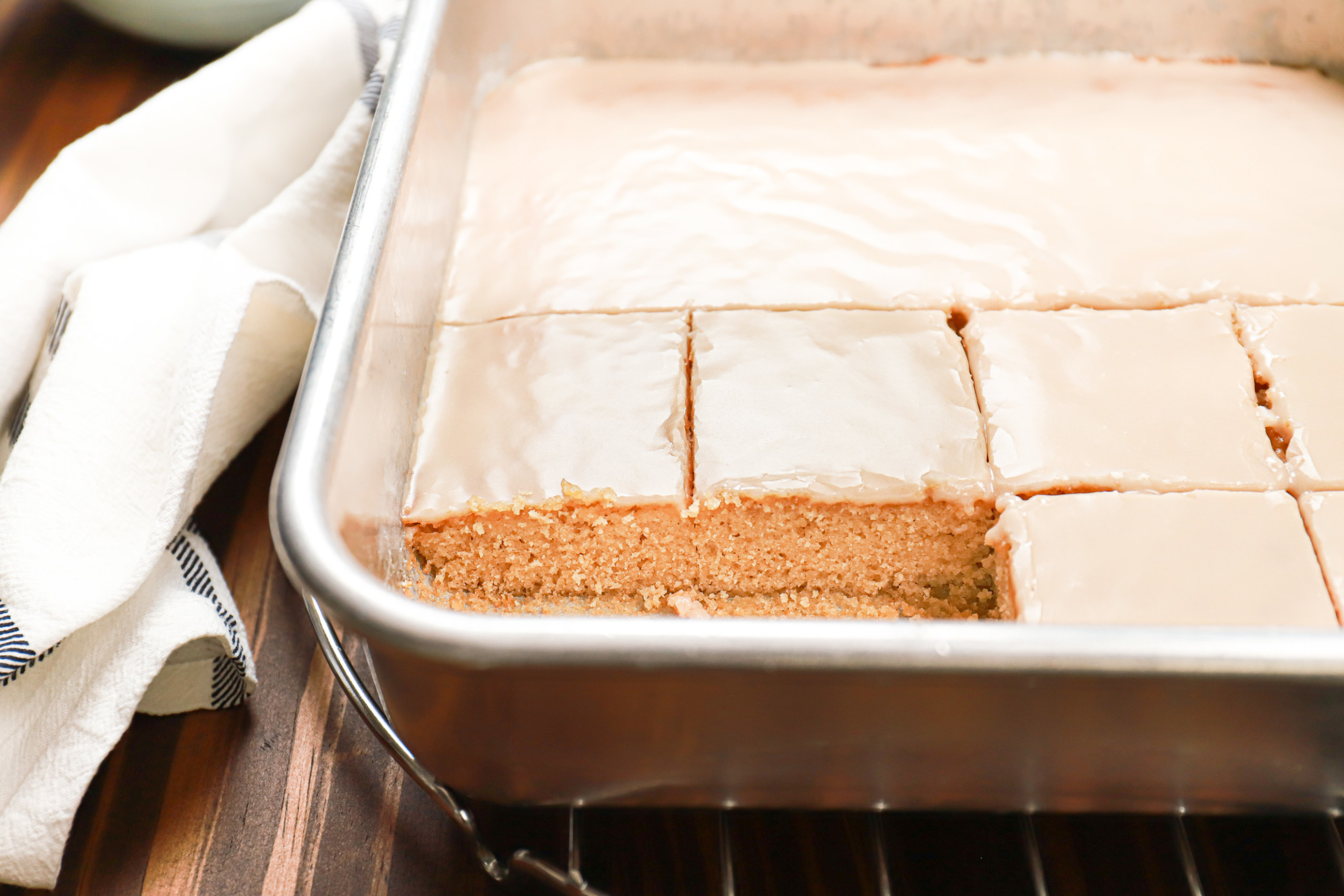 Cut maple blondies in an aluminum baking dish atop a wire cooling rack,