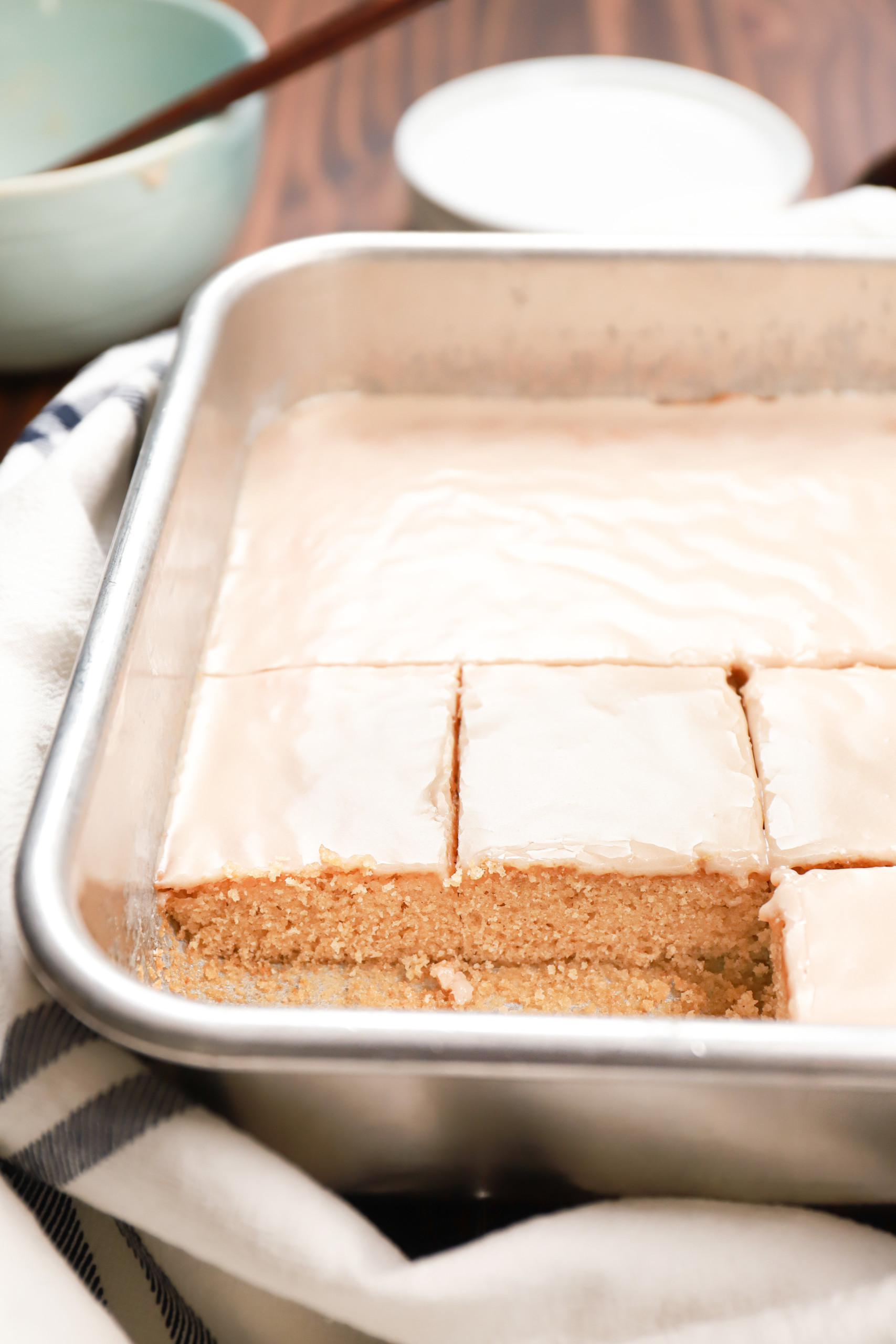 Cut maple blondies in an aluminum baking dish sitting on a wire cooling rack.