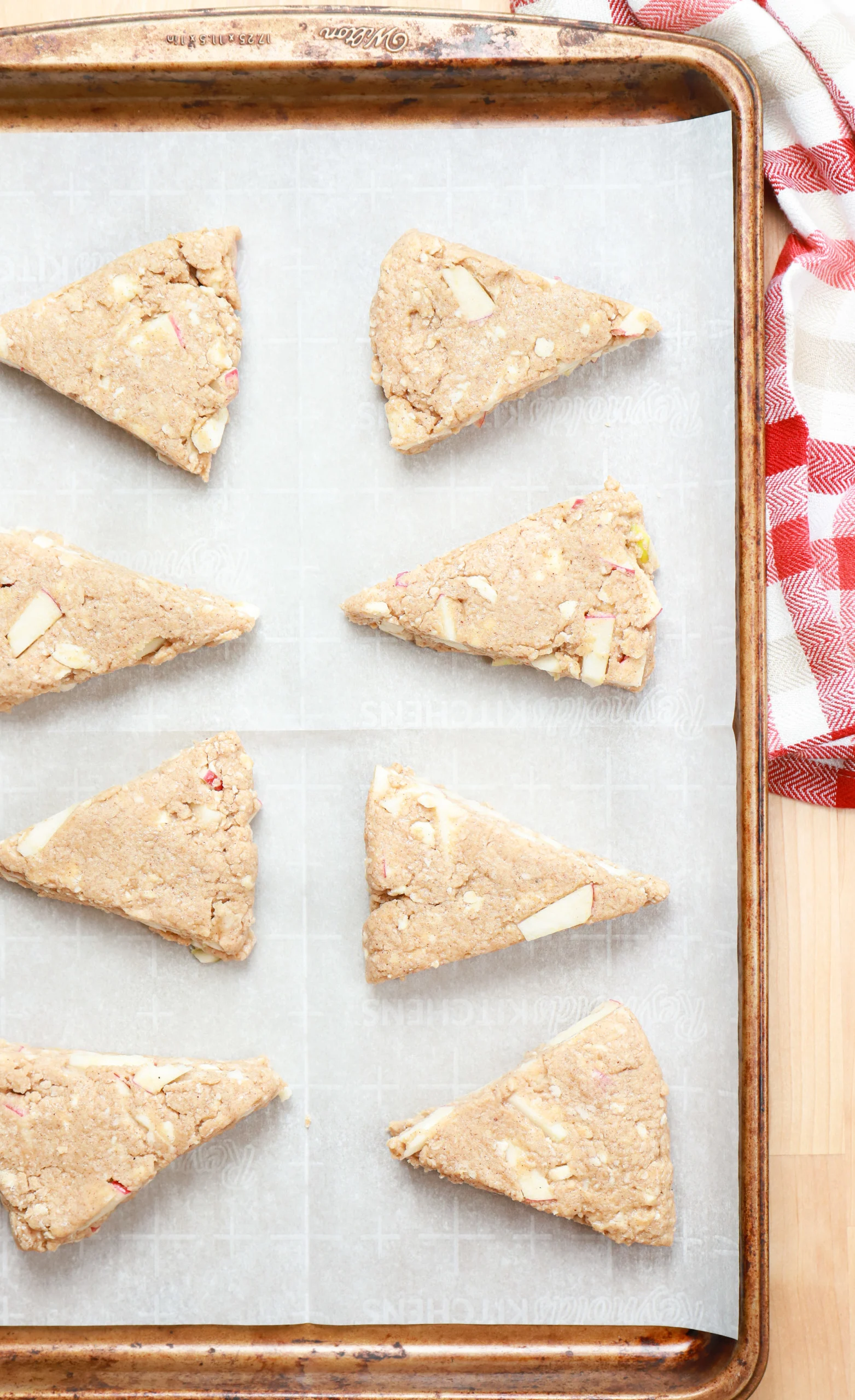 Overhead view of the apple pie scones on a parchment paper lined baking sheet before baking.