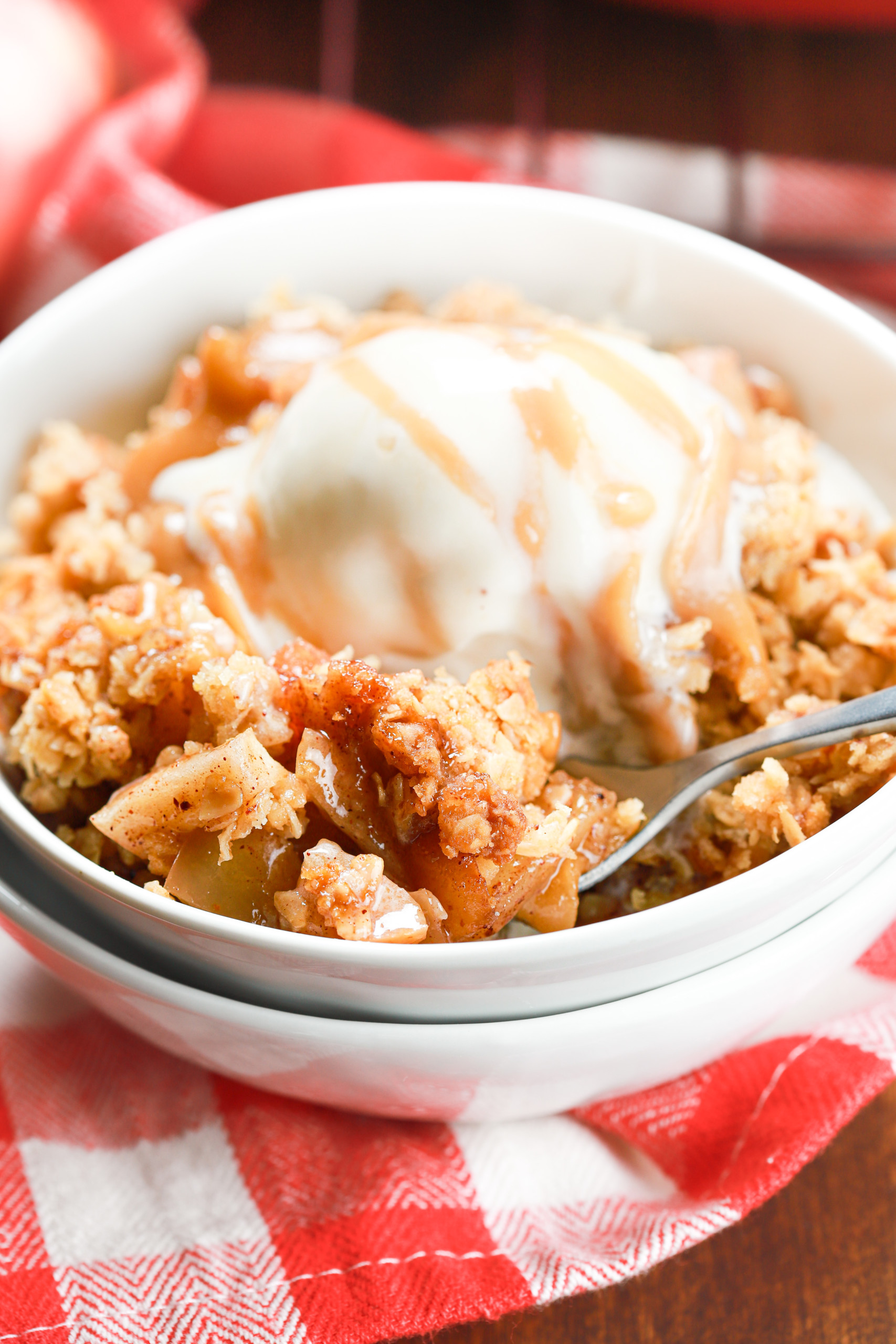 Up close side view of a scoop of caramel apple crisp in a small white bowl.