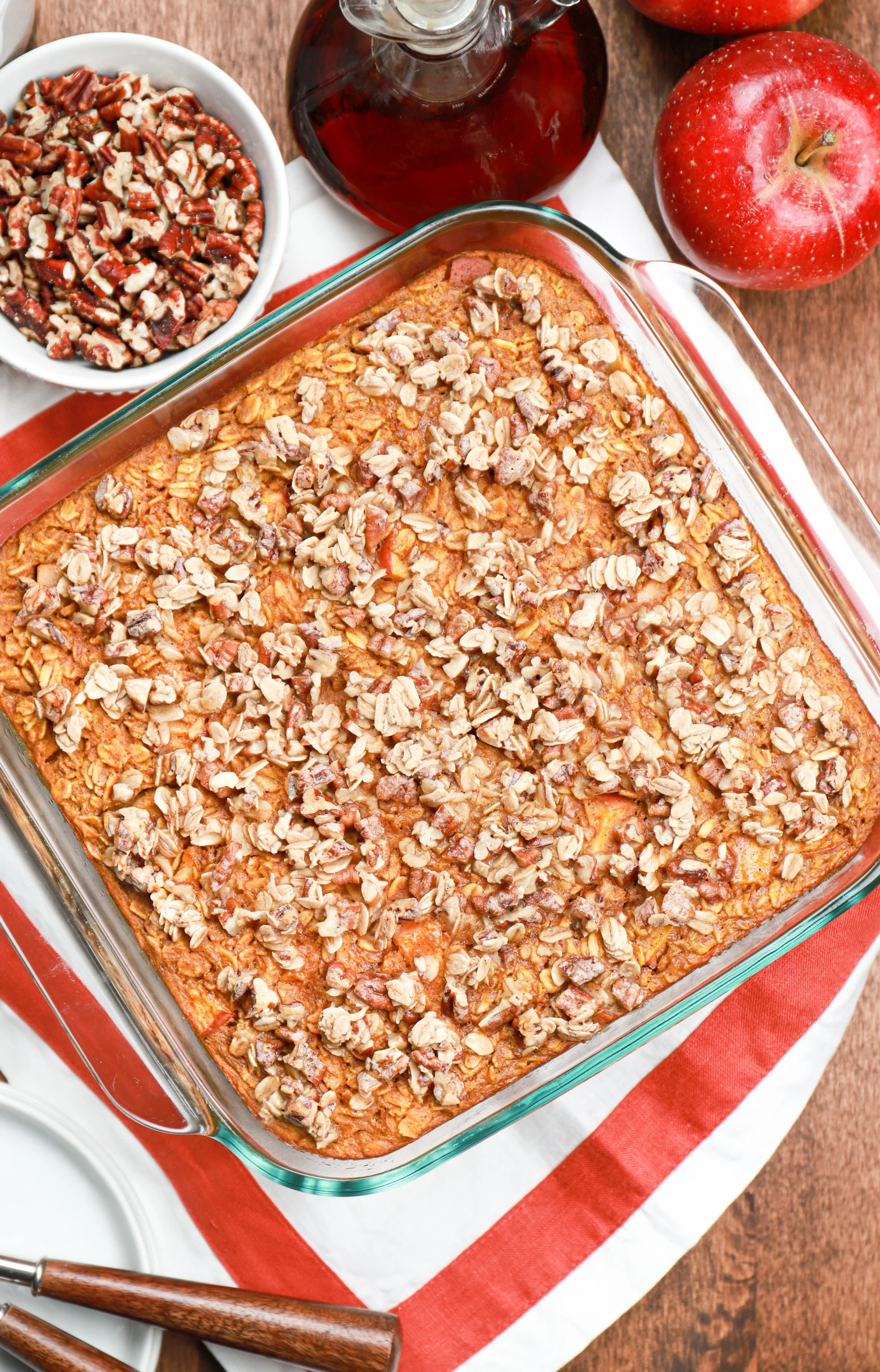 Overhead view of a batch of pumpkin apple baked oatmeal right out of the oven on a white towel with a red edging.