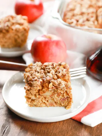 Side view of a slice of pumpkin apple baked oatmeal on a small white plate.