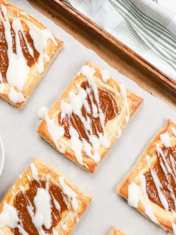 Up close overhead view of a pumpkin cream cheese danish on a parchment paper lined baking sheet.