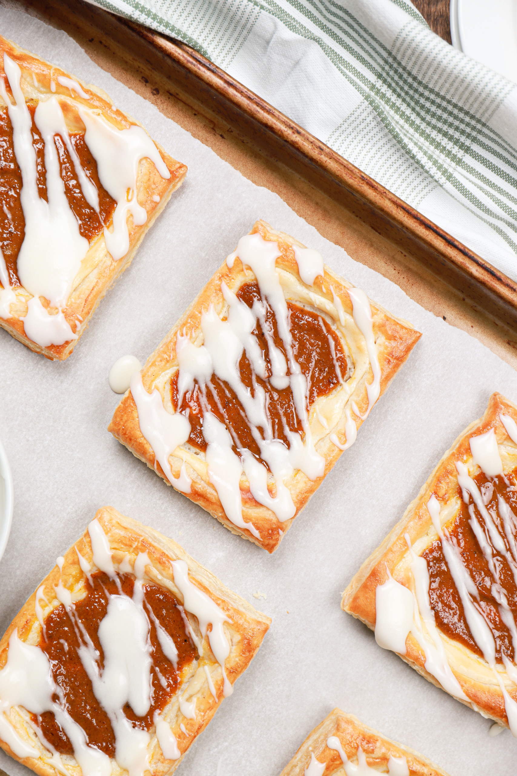 Up close overhead view of a pumpkin cream cheese danish on a parchment paper lined baking sheet.