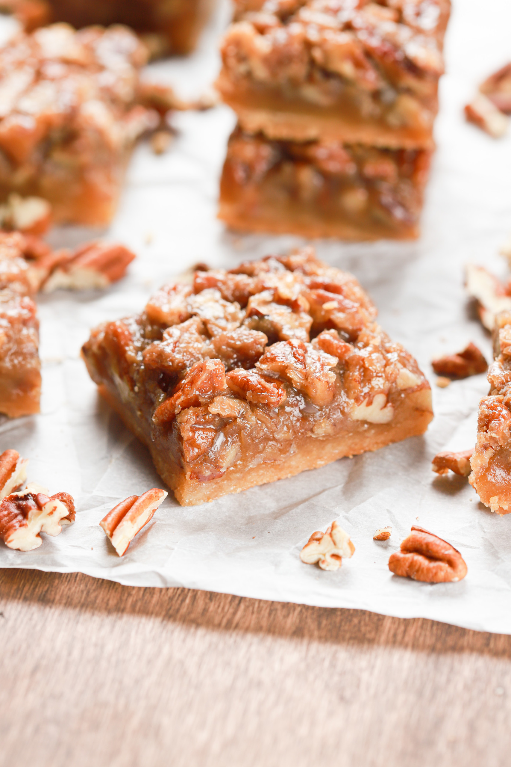 Side view of an angled maple pecan pie bar on a piece of parchment paper.