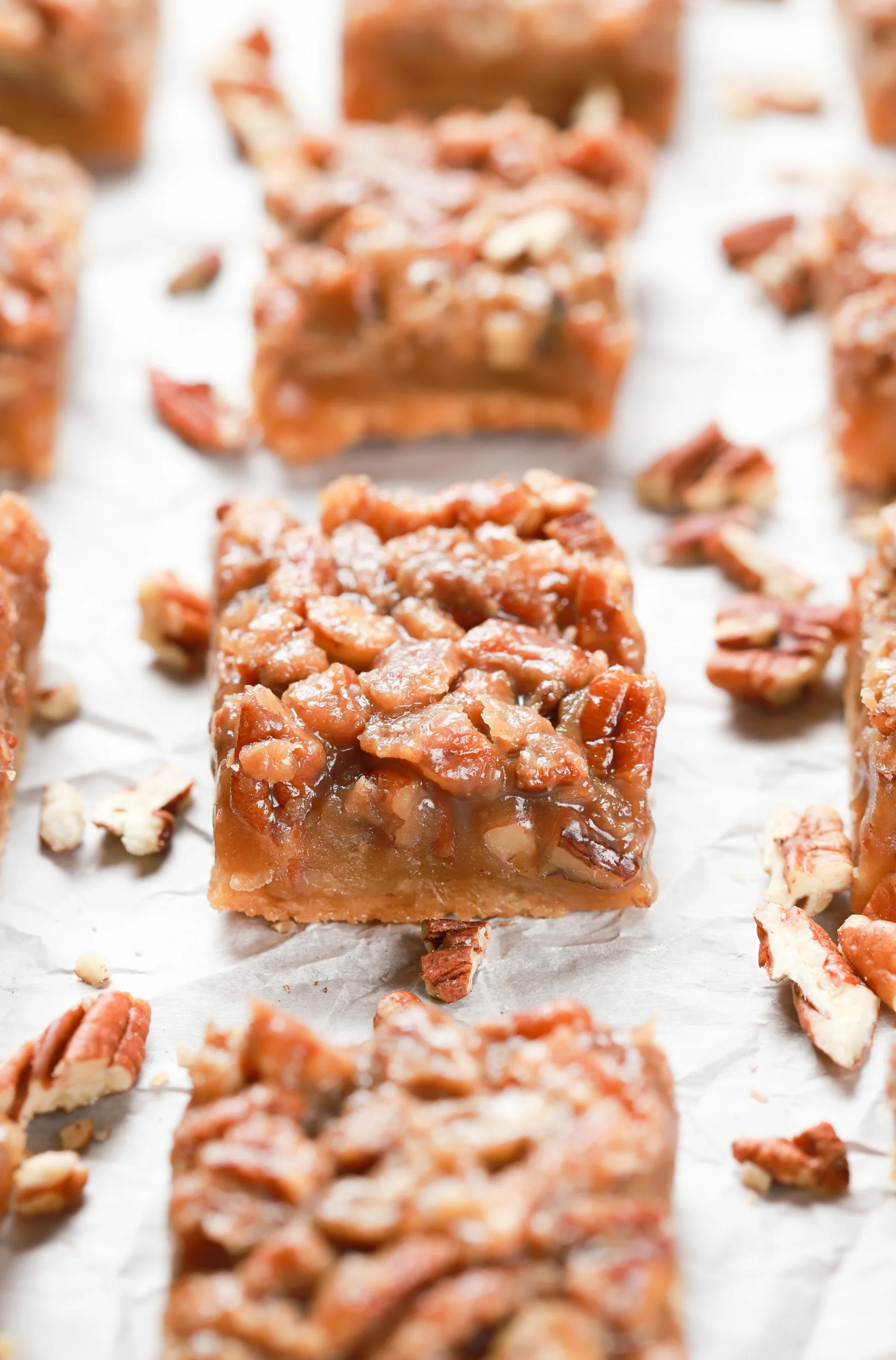 Up close side view of a maple pecan pie bars surrounded by more pie bars.