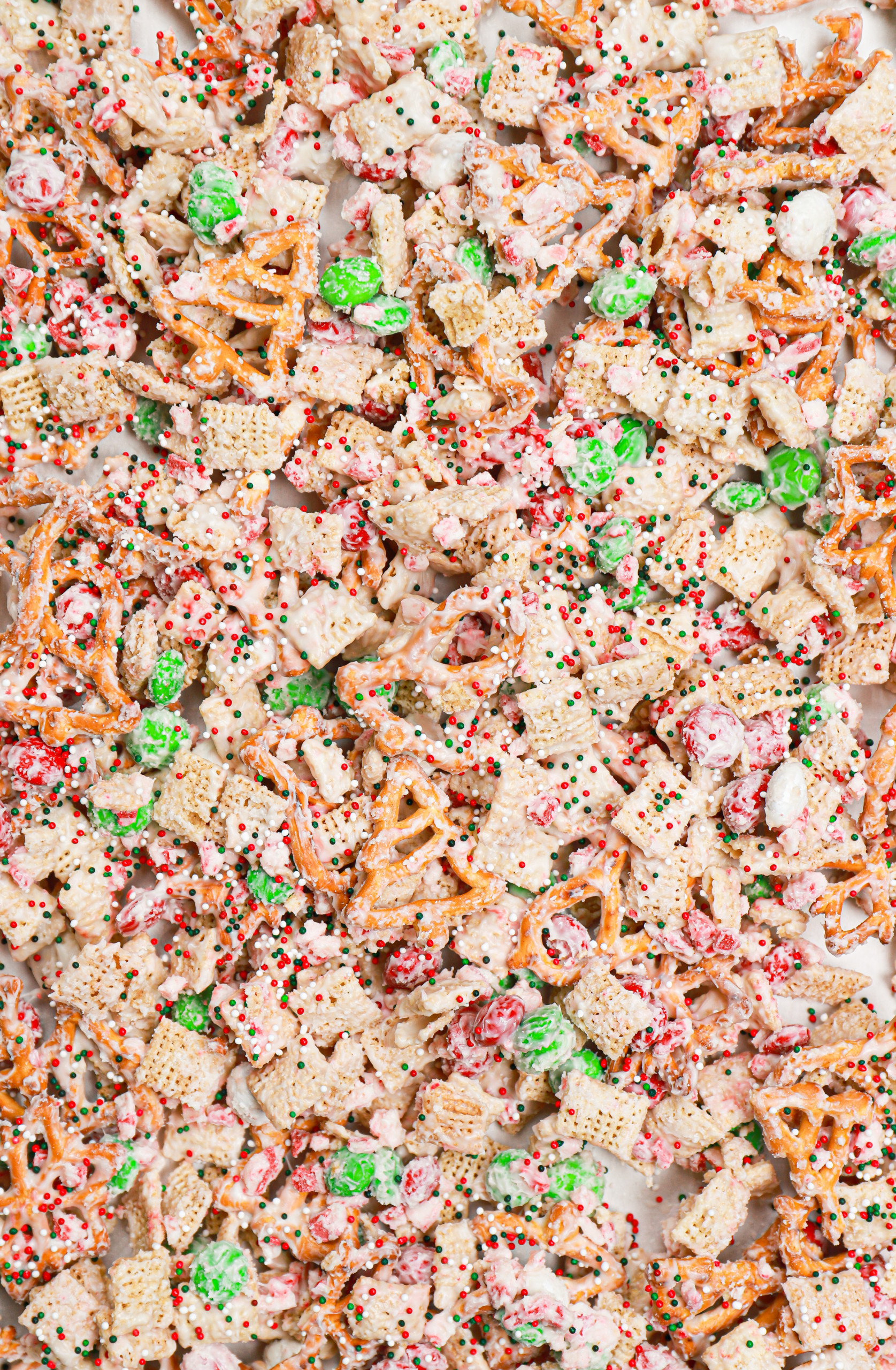 Up close overhead view of peppermint crunch snack mix on a parchment paper lined aluminum baking sheet.