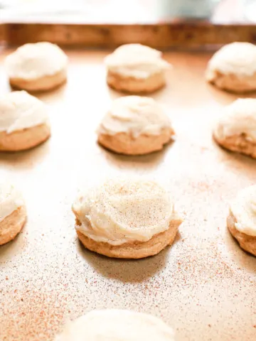 Up close side view of a frosted eggnog cookie on a baking sheet.