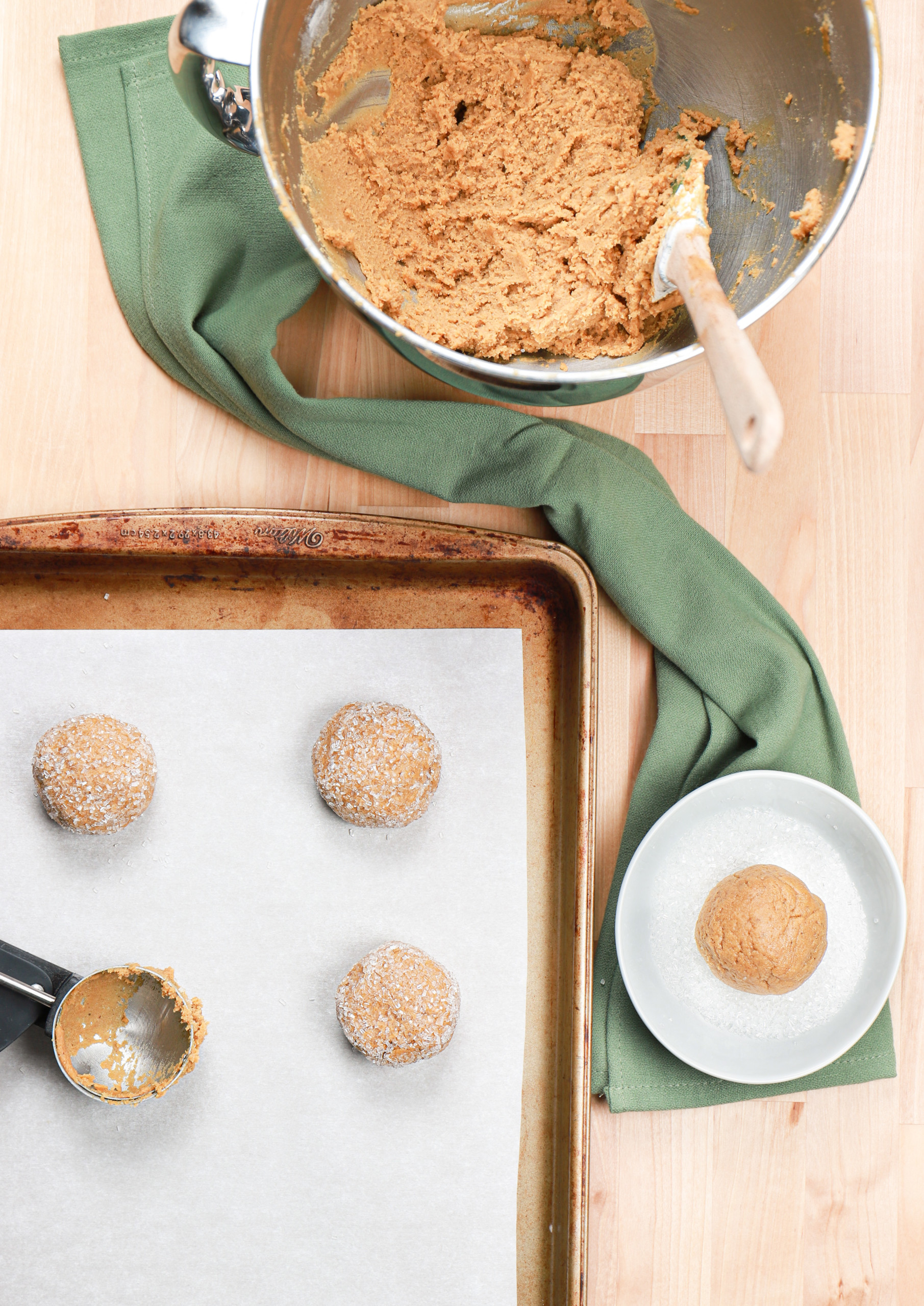 Molasses cookie dough balls on a parchment paper lined baking sheet before baking.