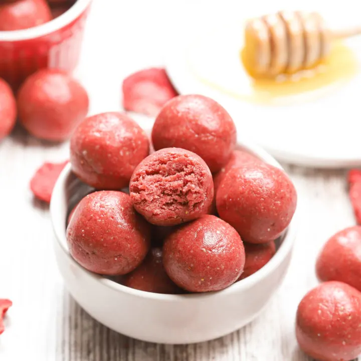 Up close view of a strawberry vanilla energy ball with a bite taken out of it.