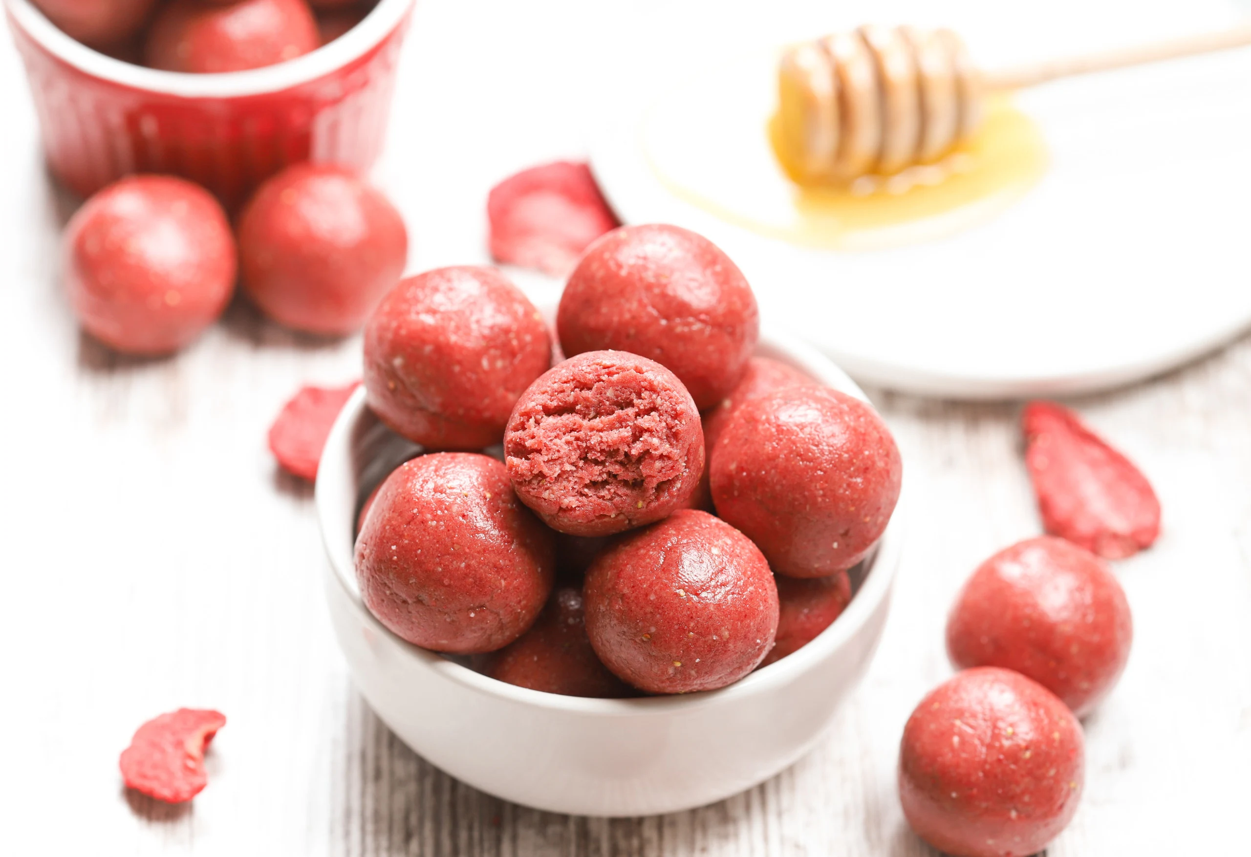 Up close view of a strawberry vanilla energy ball with a bite taken out of it.