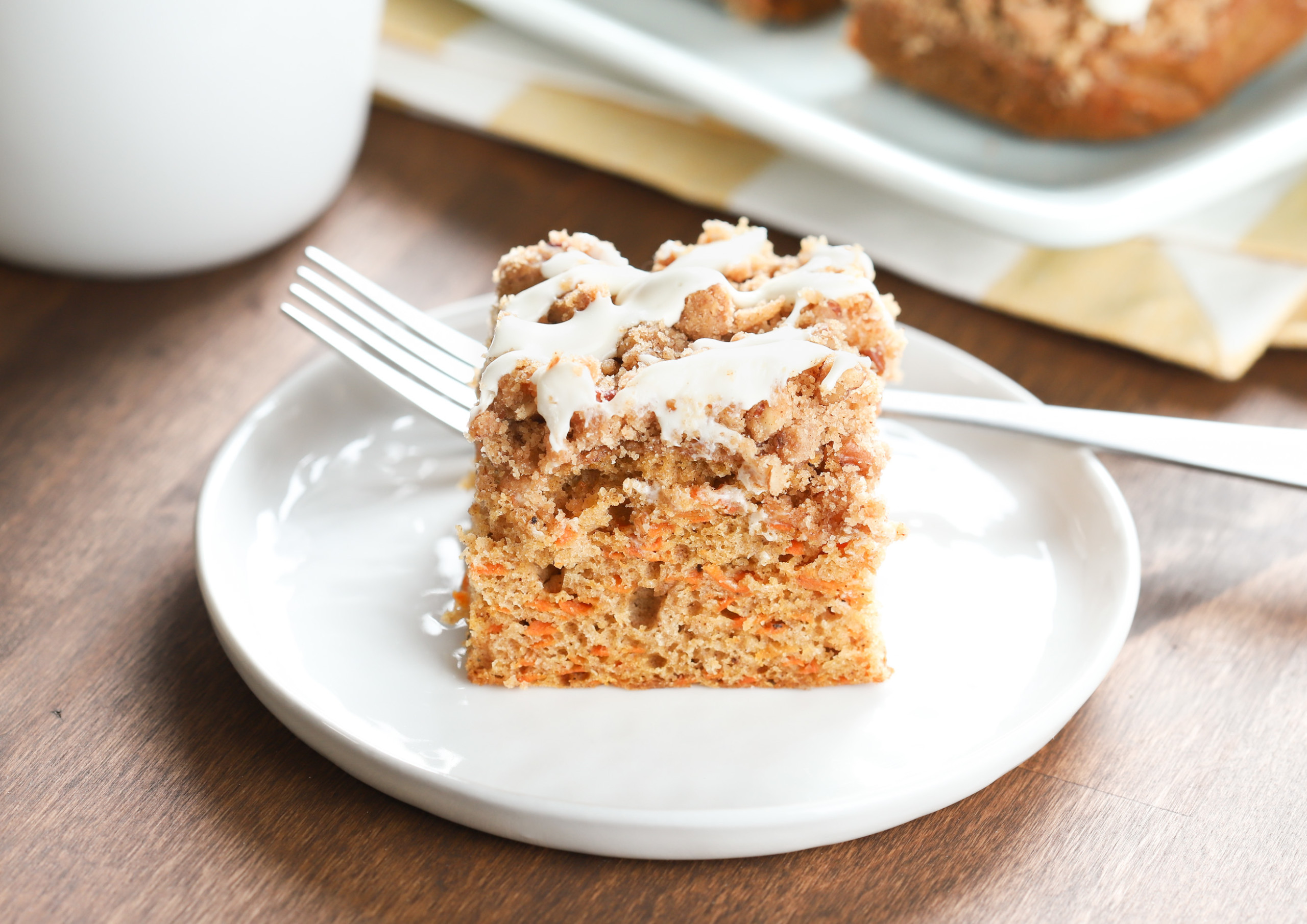 Up close side view of a piece of carrot cake coffee cake on a small white plate.