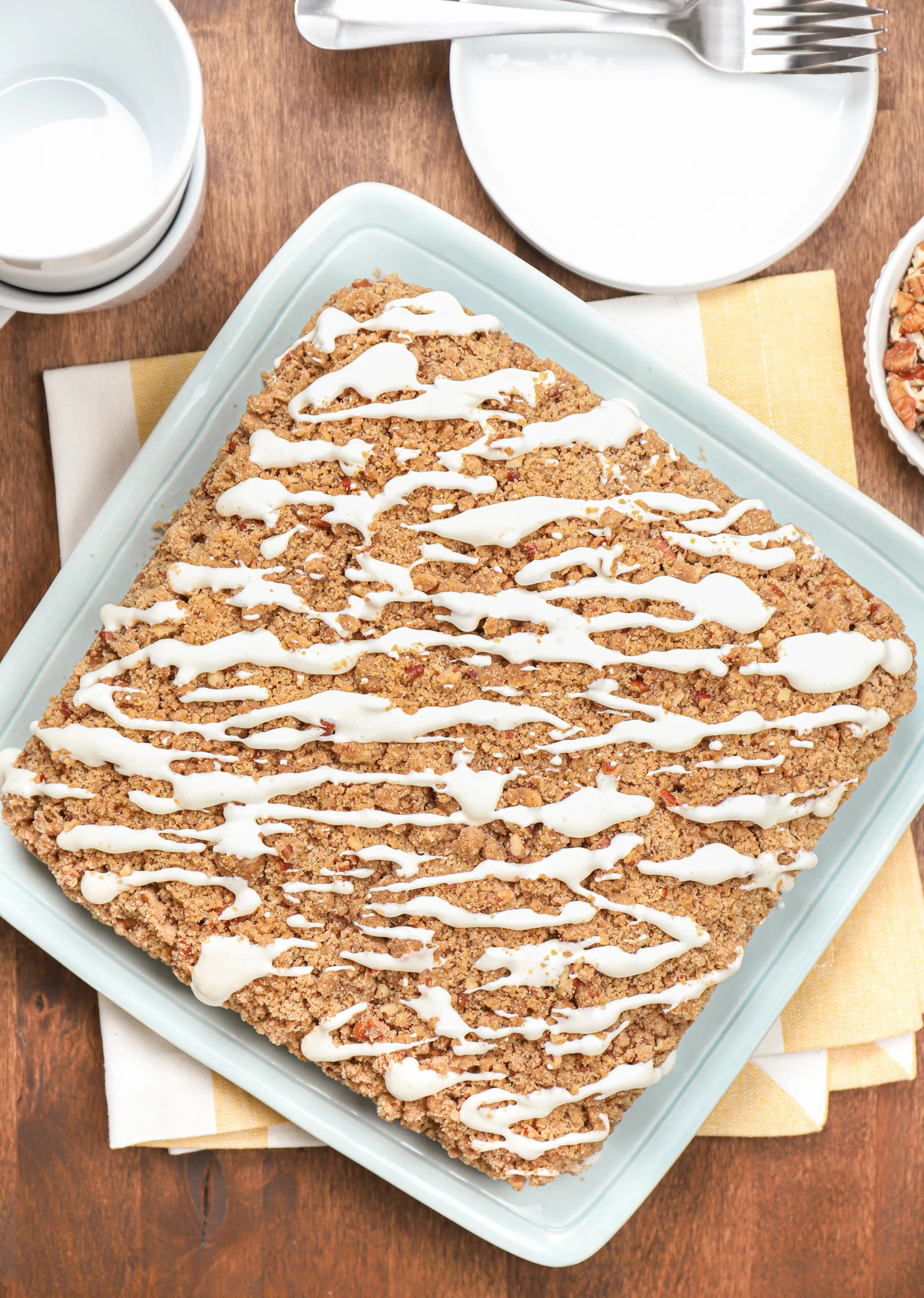 Overhead view of a cream cheese glazed carrot cake coffee cake on a light blue plate before cutting it into pieces.