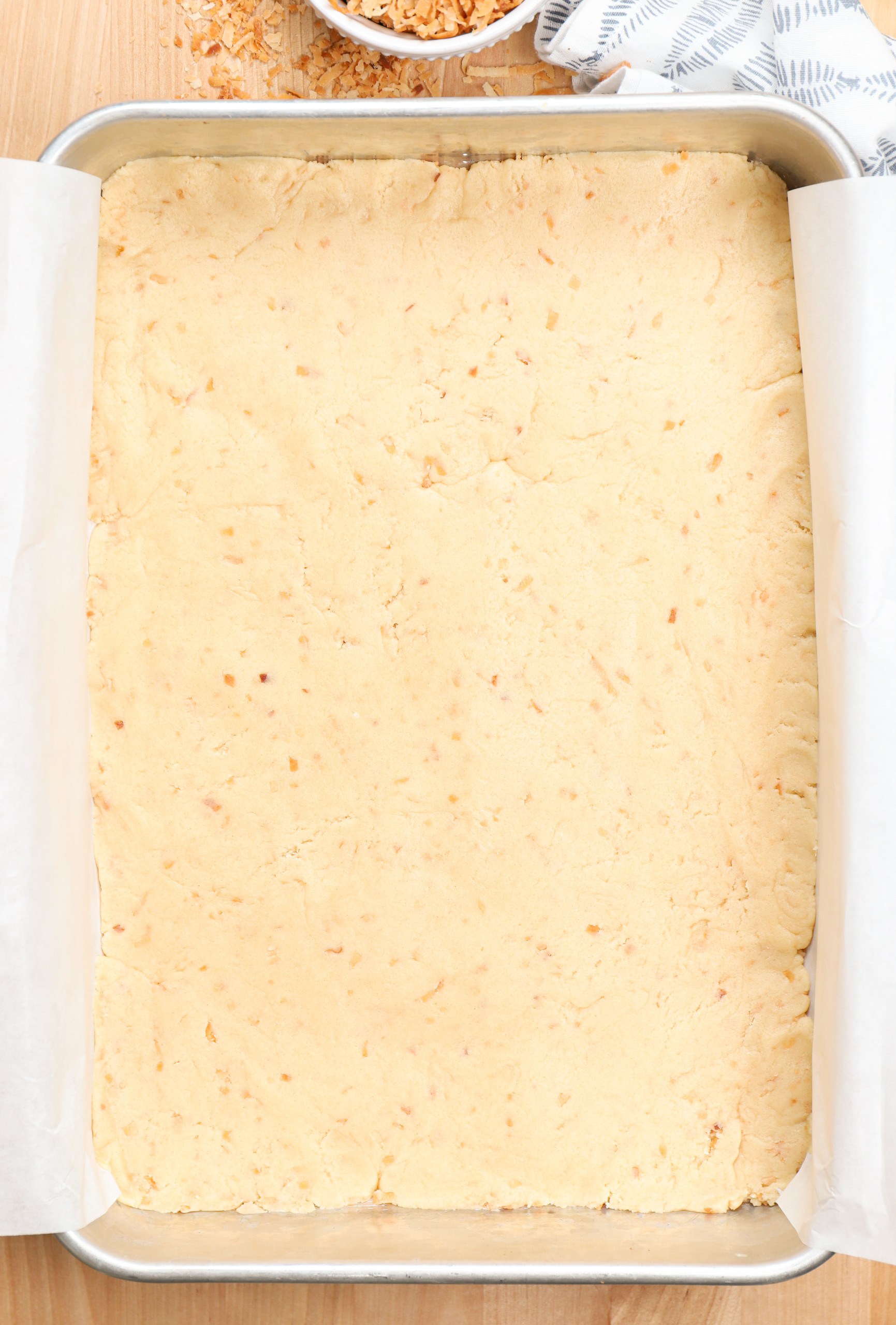 Overhead view of coconut sugar cookie bars in a baking dish before baking.