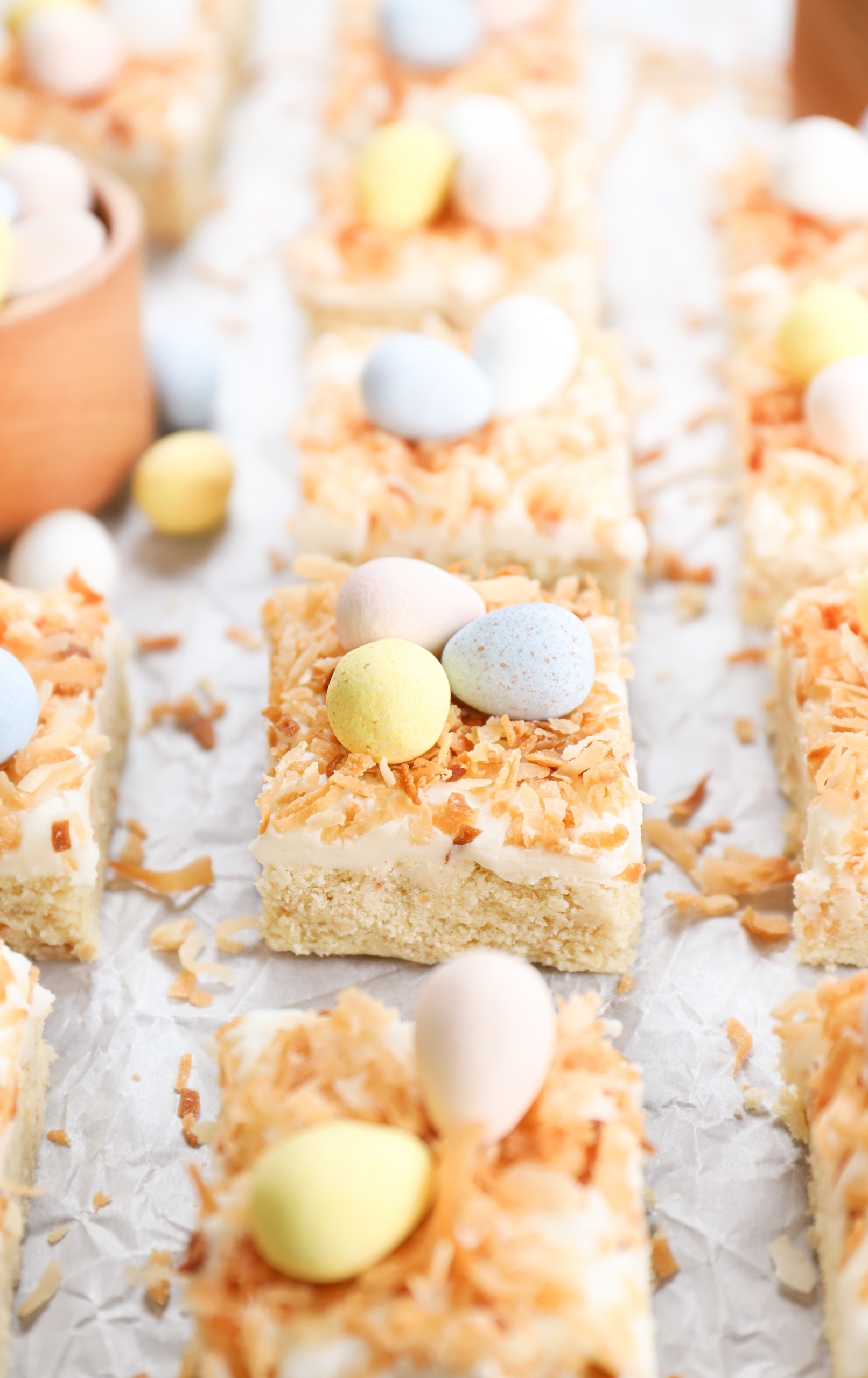 Up close side view of a frosted coconut sugar cookie bar with the remainder of the bars in the background.