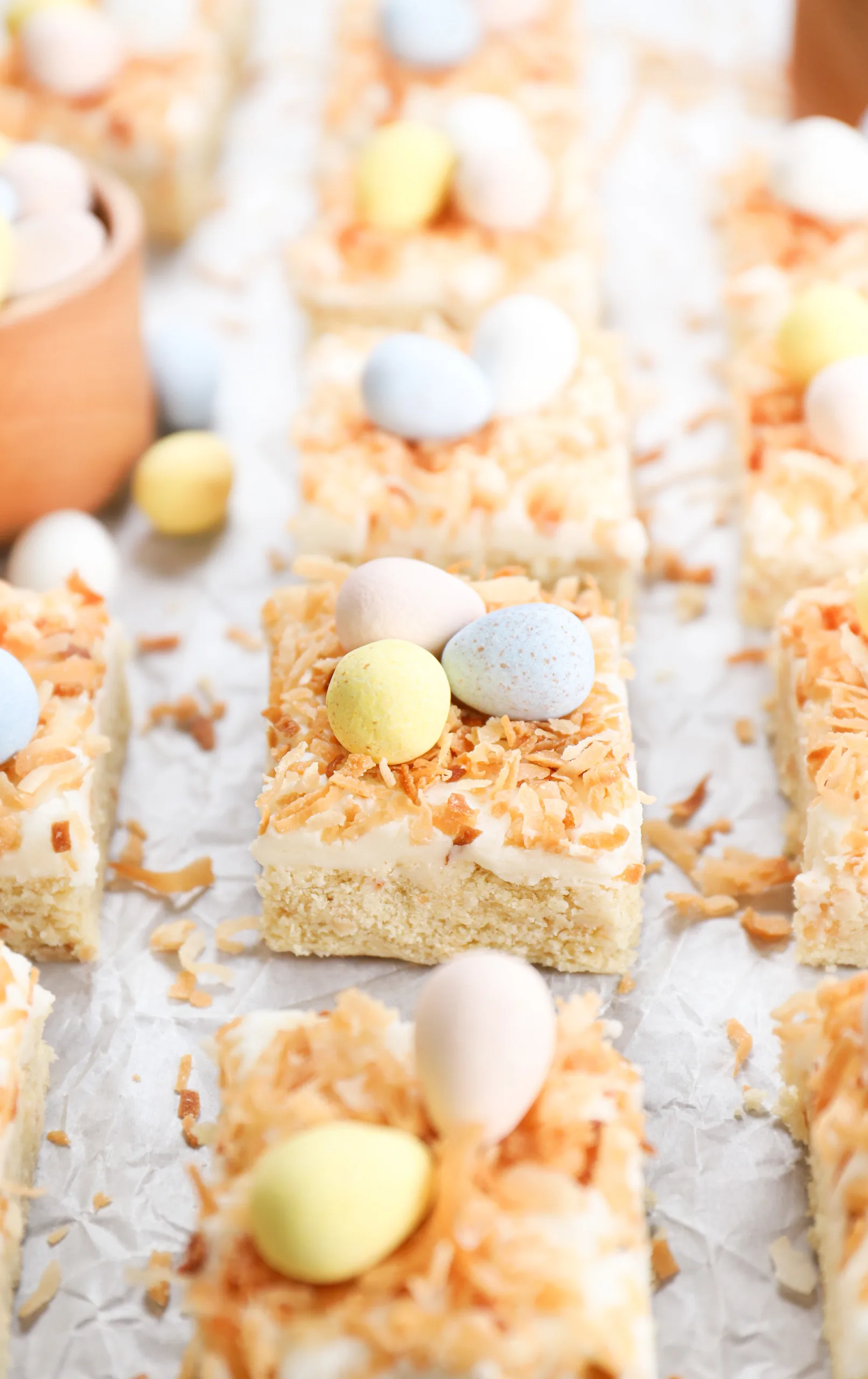 Up close side view of a frosted coconut sugar cookie bar with the remainder of the bars in the background.