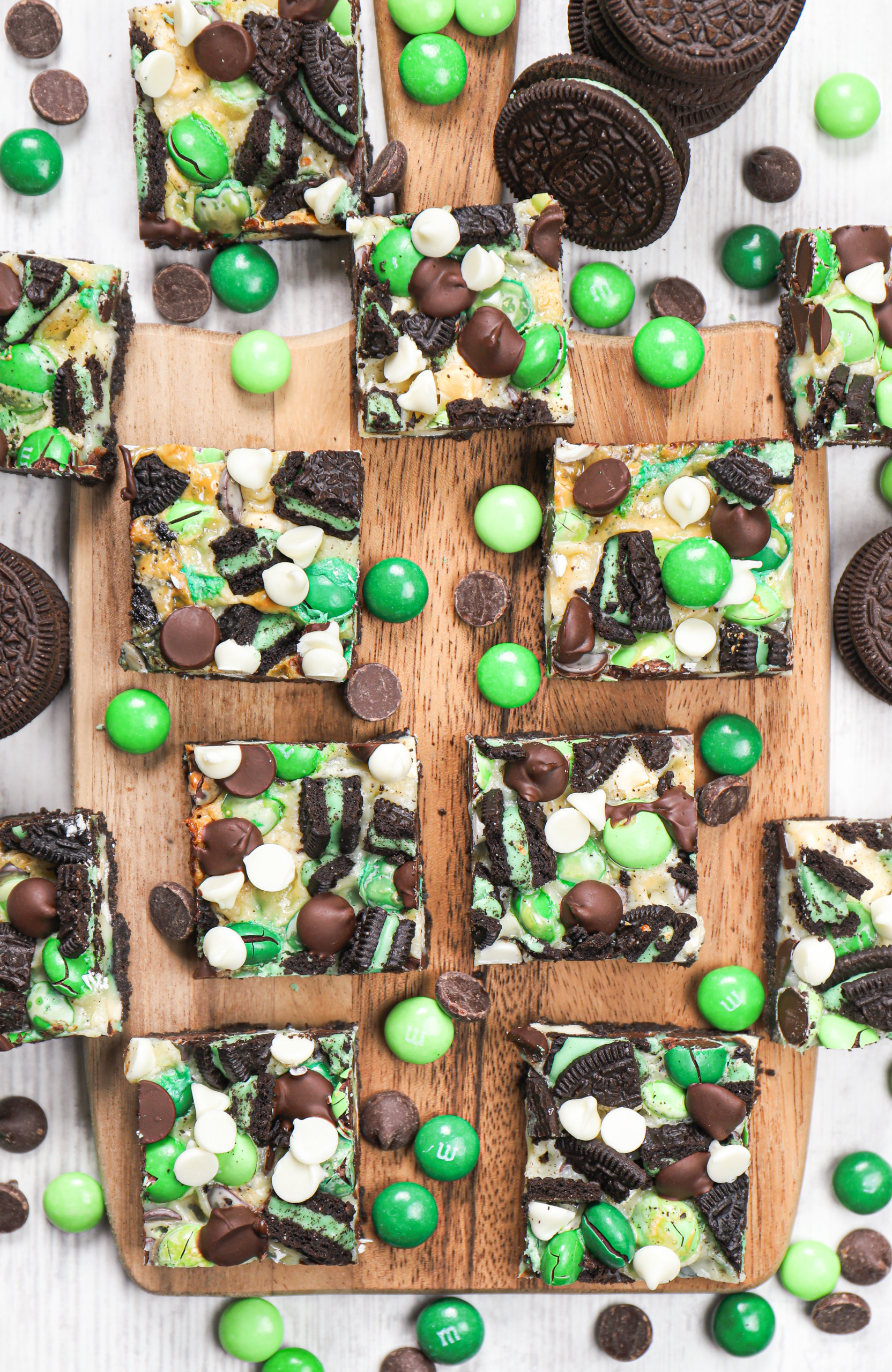 Overhead view of a batch of mint chocolate seven layer bars on a wooden cutting board.