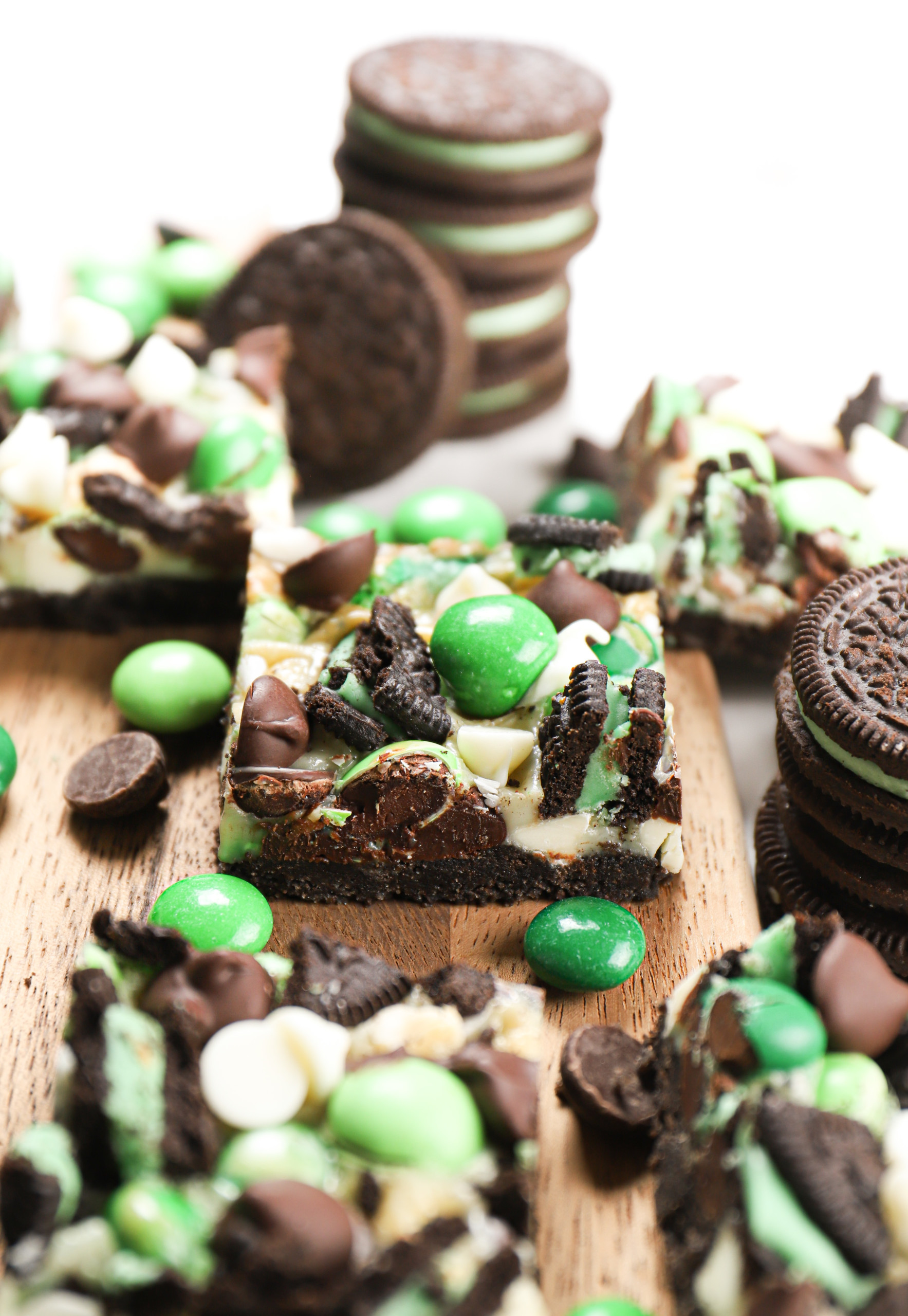 Up close side view of a mint chocolate seven layer bar surrounded by additional bars on a wooden cutting board.