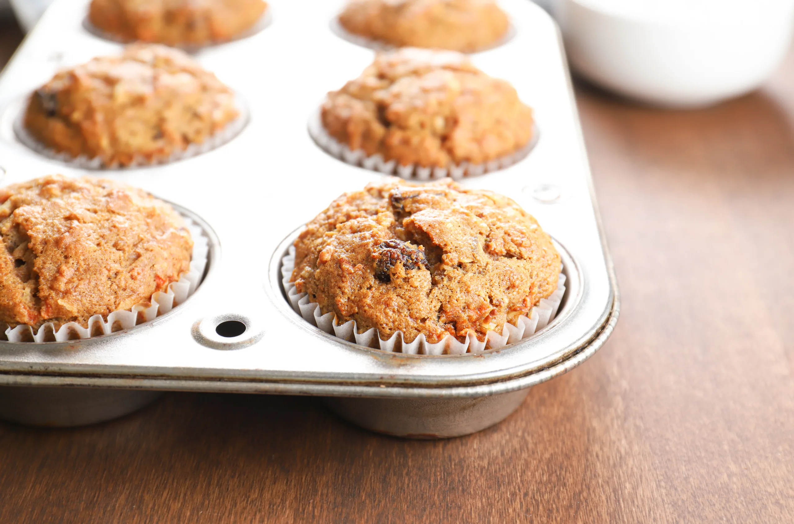 Up close side view of a morning glory muffin in an aluminum muffin tin.