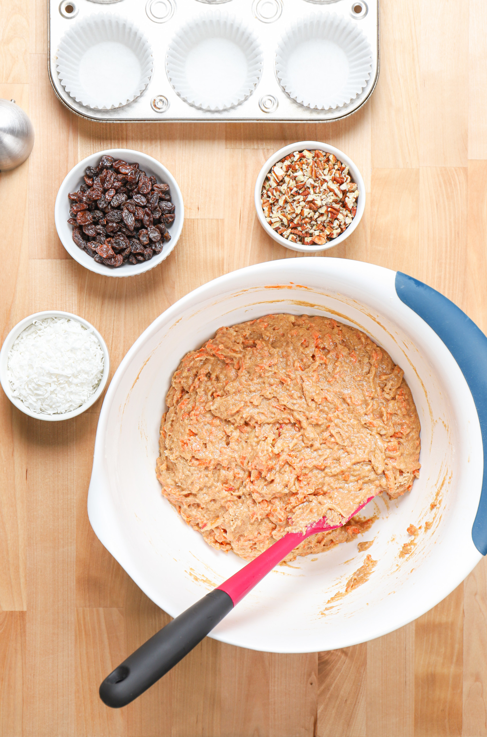 Overhead view of the muffin batter in a large bowl with additional addins in smaller bowls.