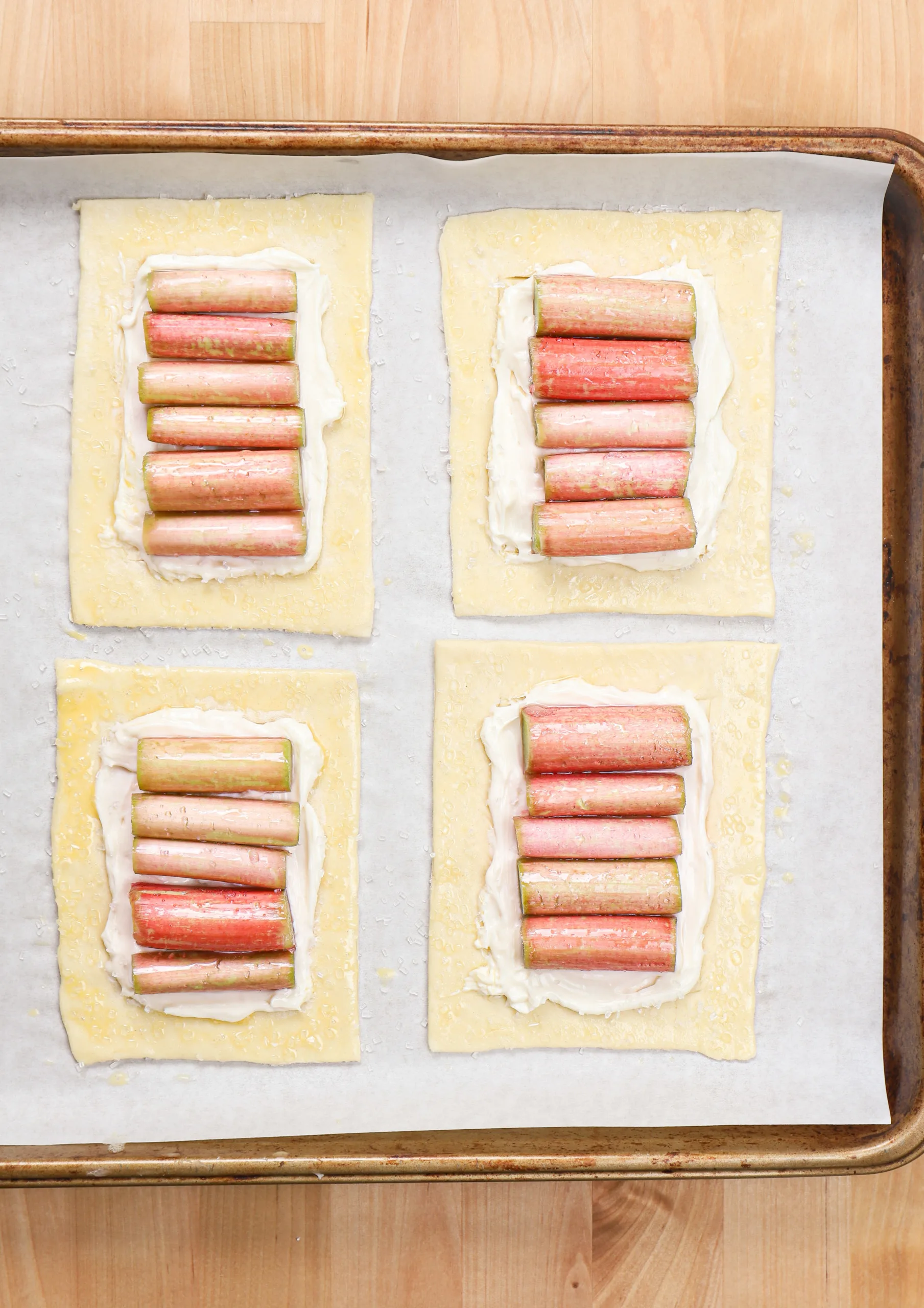 Overhead view of four rhubarb cream cheese danishes on a baking sheet right before baking.