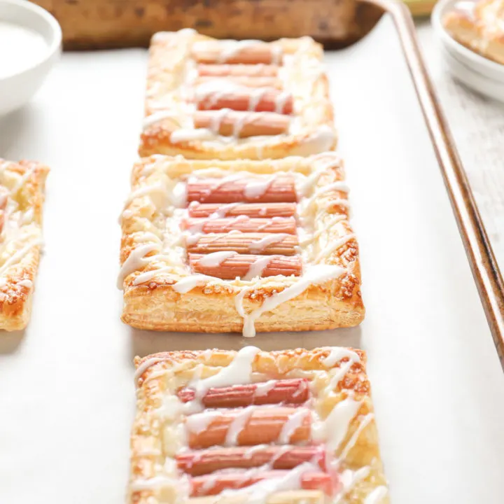 Up close side view of a rhubarb cream cheese danish on a parchment paper lined baking sheet.