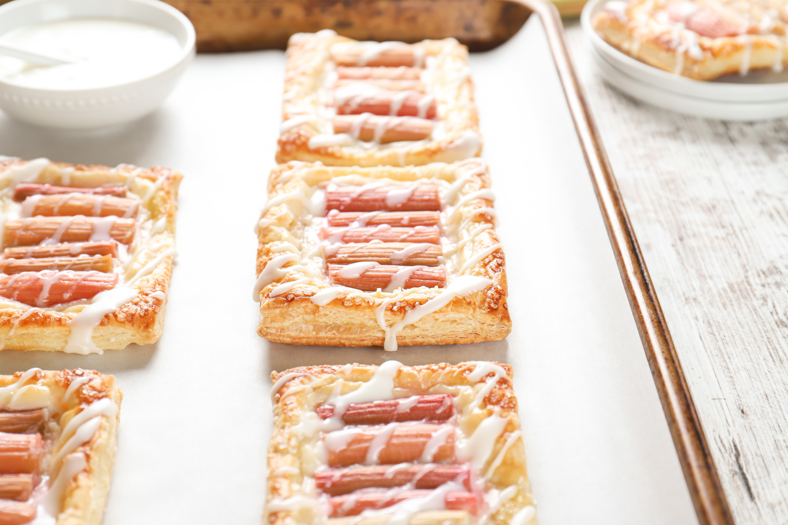 Up close side view of a rhubarb cream cheese danish on a parchment paper lined baking sheet.