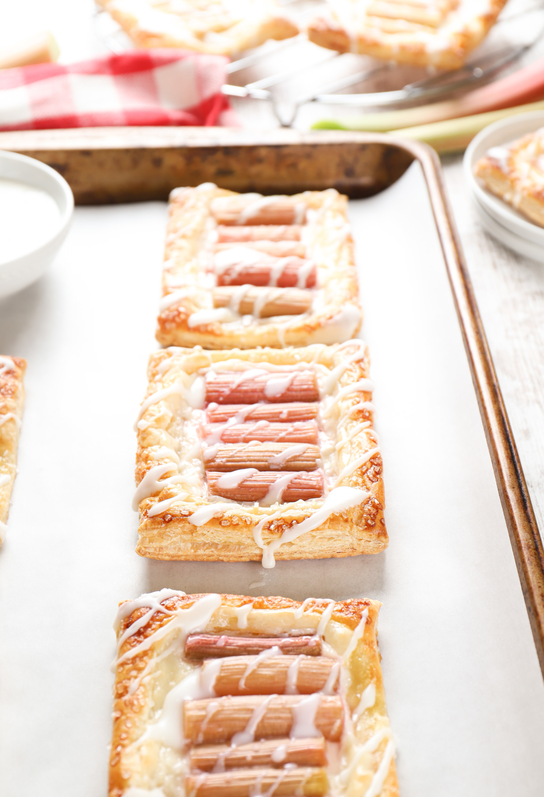 Up close side view to show the flaky layers of a rhubarb cream cheese danish on a parchment paper lined baking sheet.