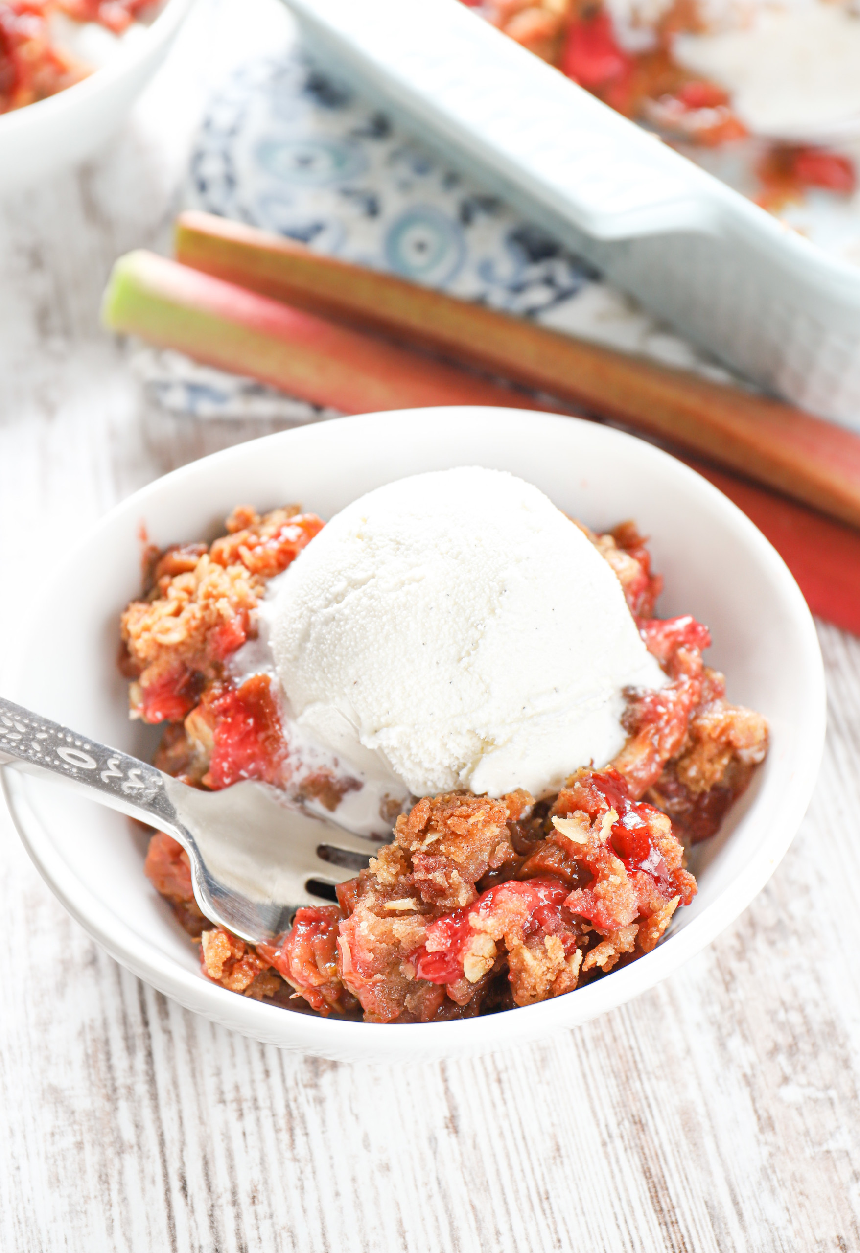 Up close view of a scoop of strawberry rhubarb crisp in a small white bowl.