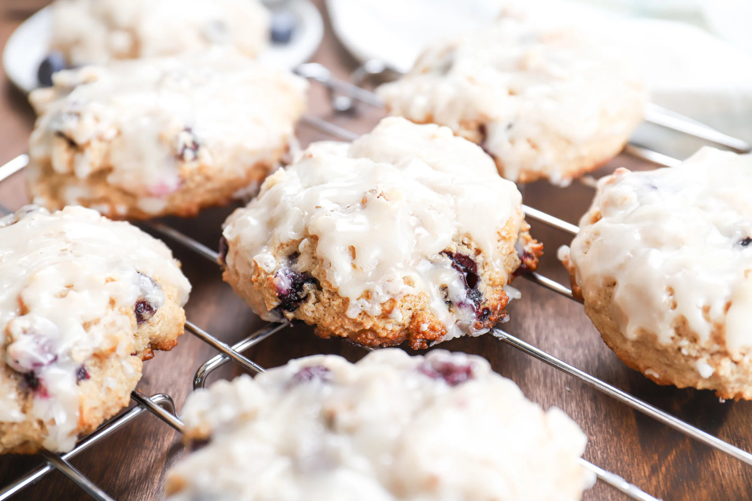 Up close side view of a baked blueberry fritter on a cooling rack surrounded by other fritters.