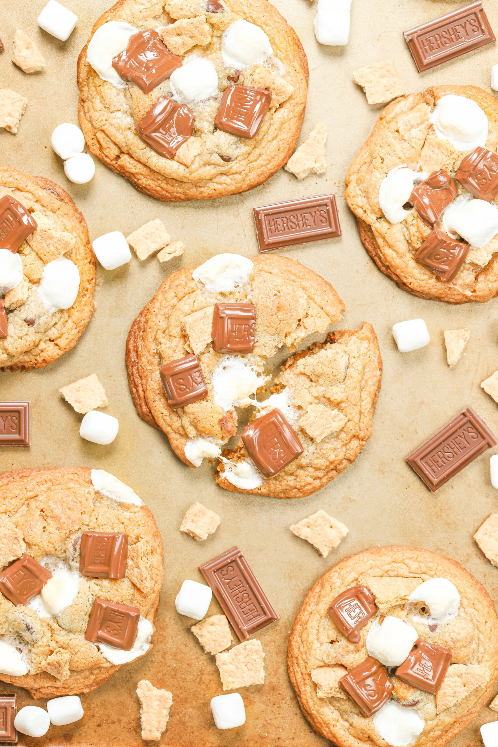 Overhead view of a bakery style smores cookie broken in half to show melting marshmallows.
