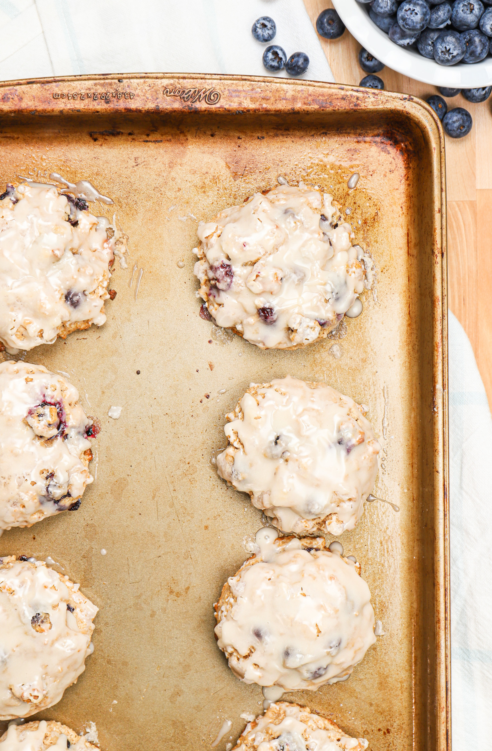 Overhead view of a batch of baked blueberry fritters on an aluminum baking sheet.