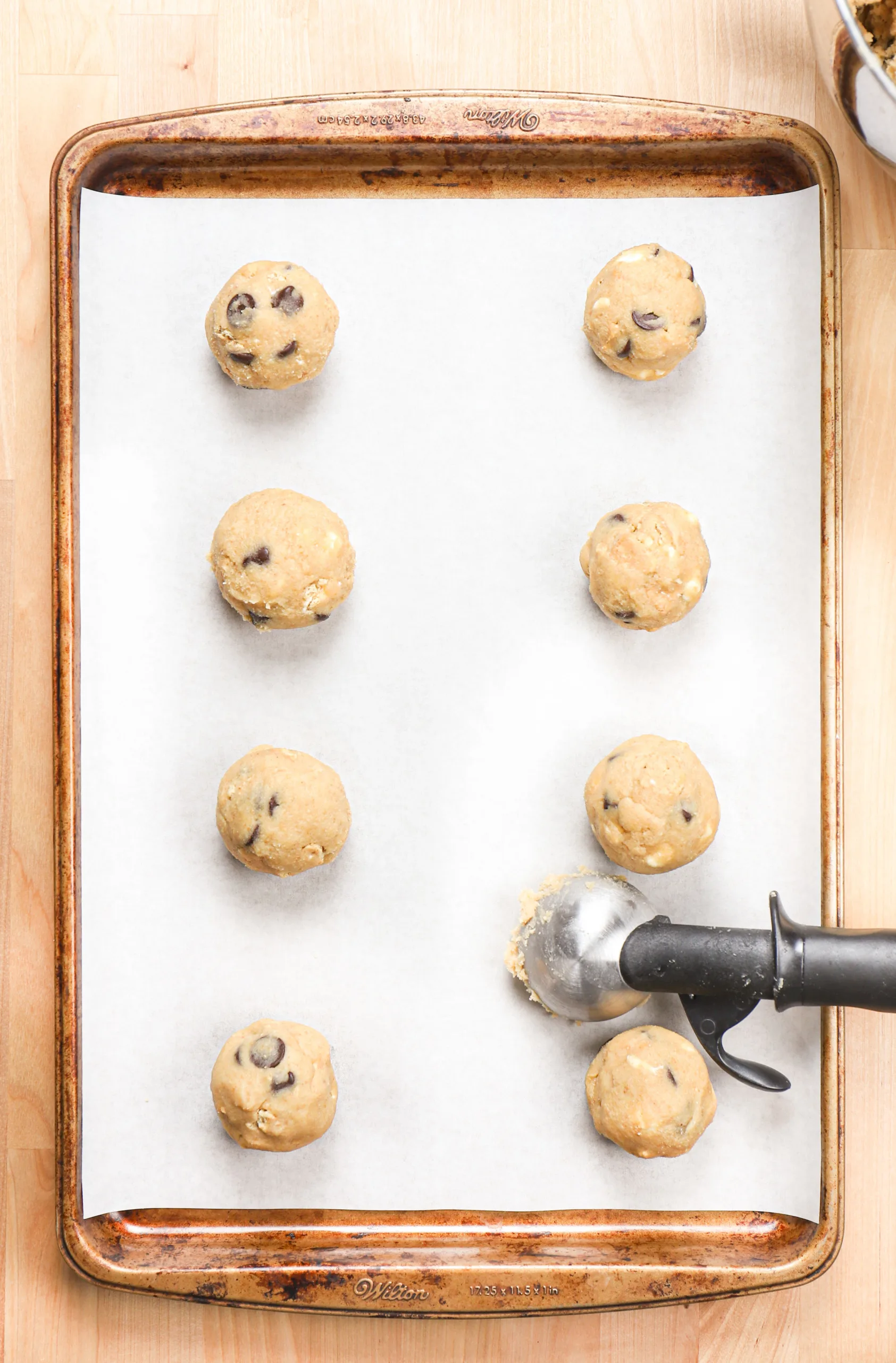 Overhead view of smores cookie dough balls on a parchment paper lined baking sheet before baking.