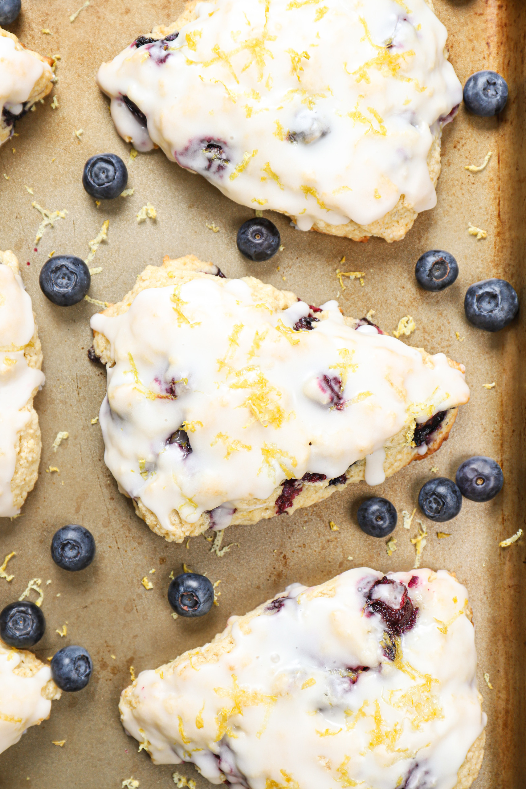 Up close overhead view of a lemon blueberry scone on an aluminum baking sheet.