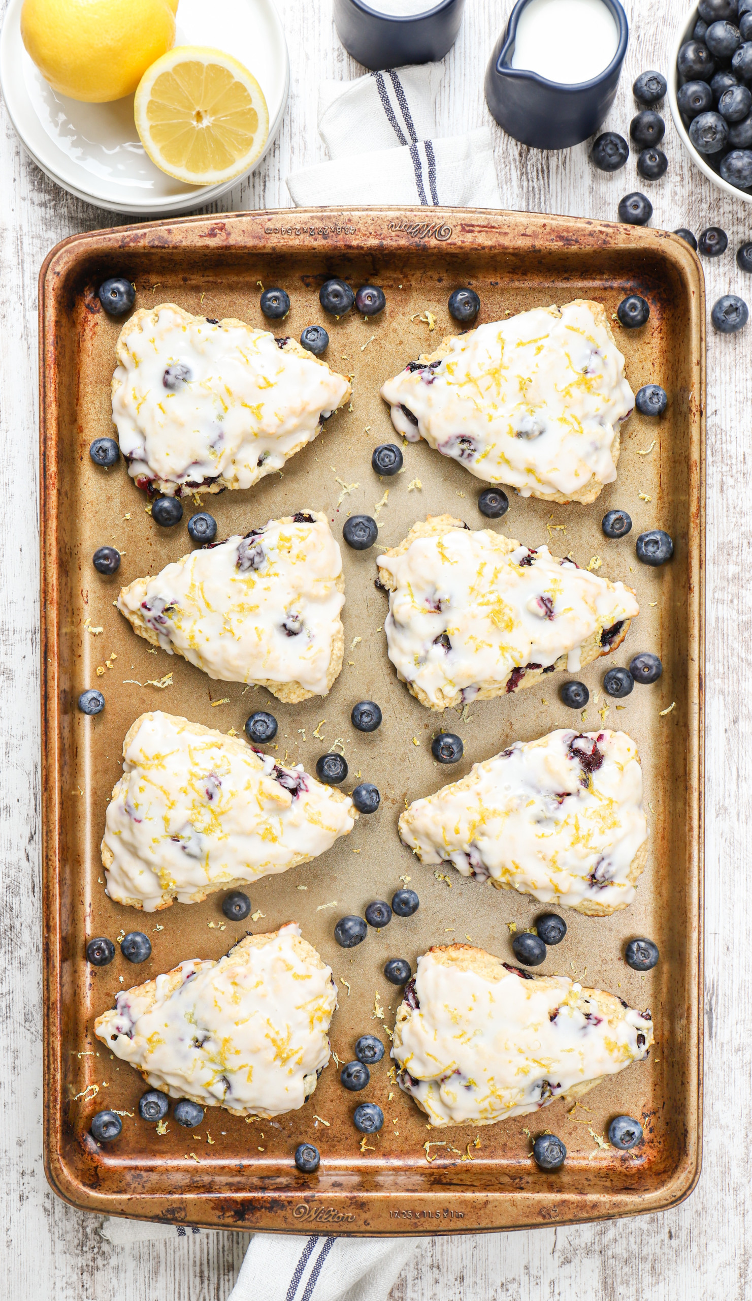 Overhead view of a batch of lemon blueberry scones on an aluminum baking sheet.