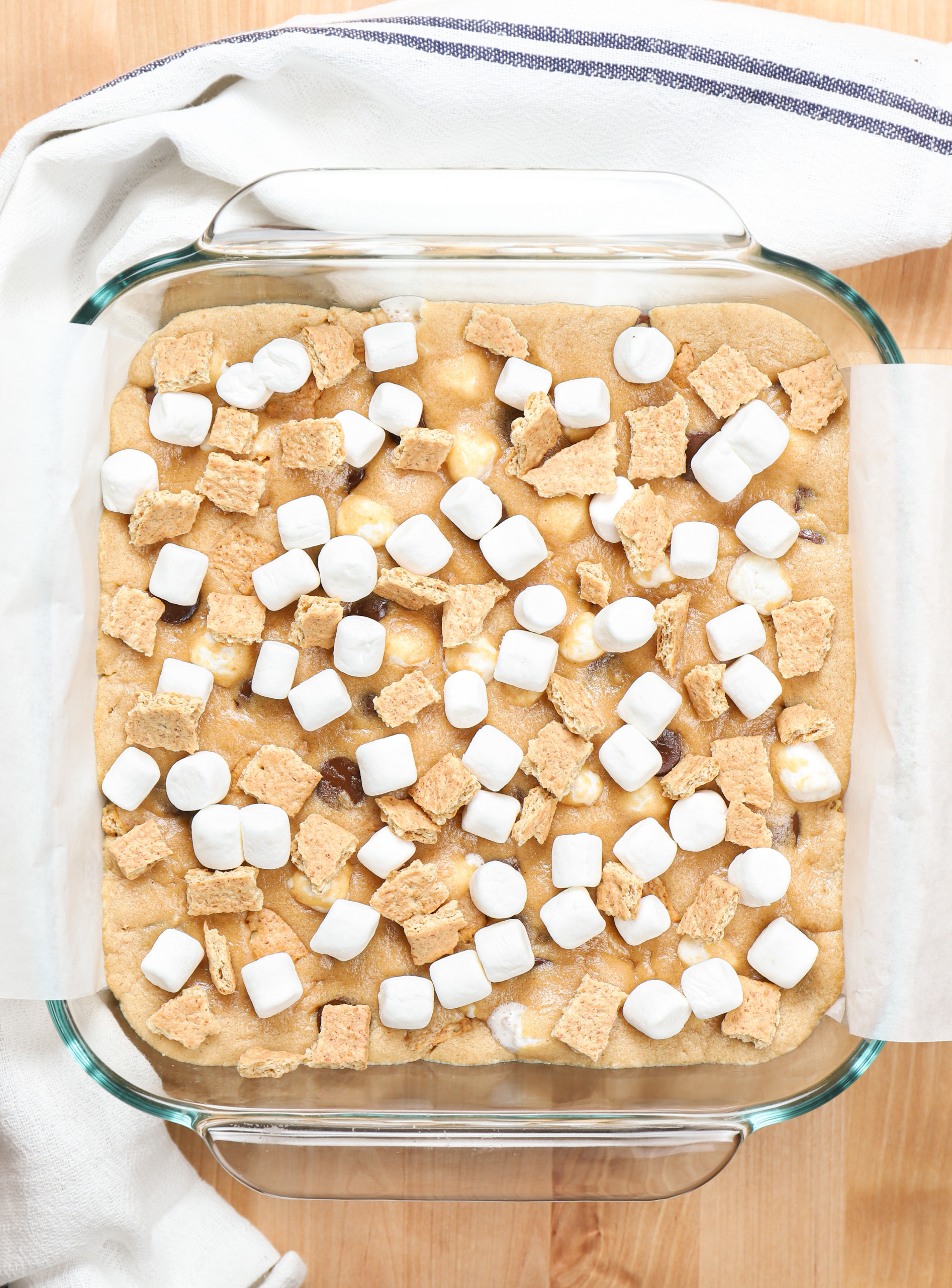 Overhead view of a pan of peanut butter smores bars halfway through baking with mini marshmallows added on top.