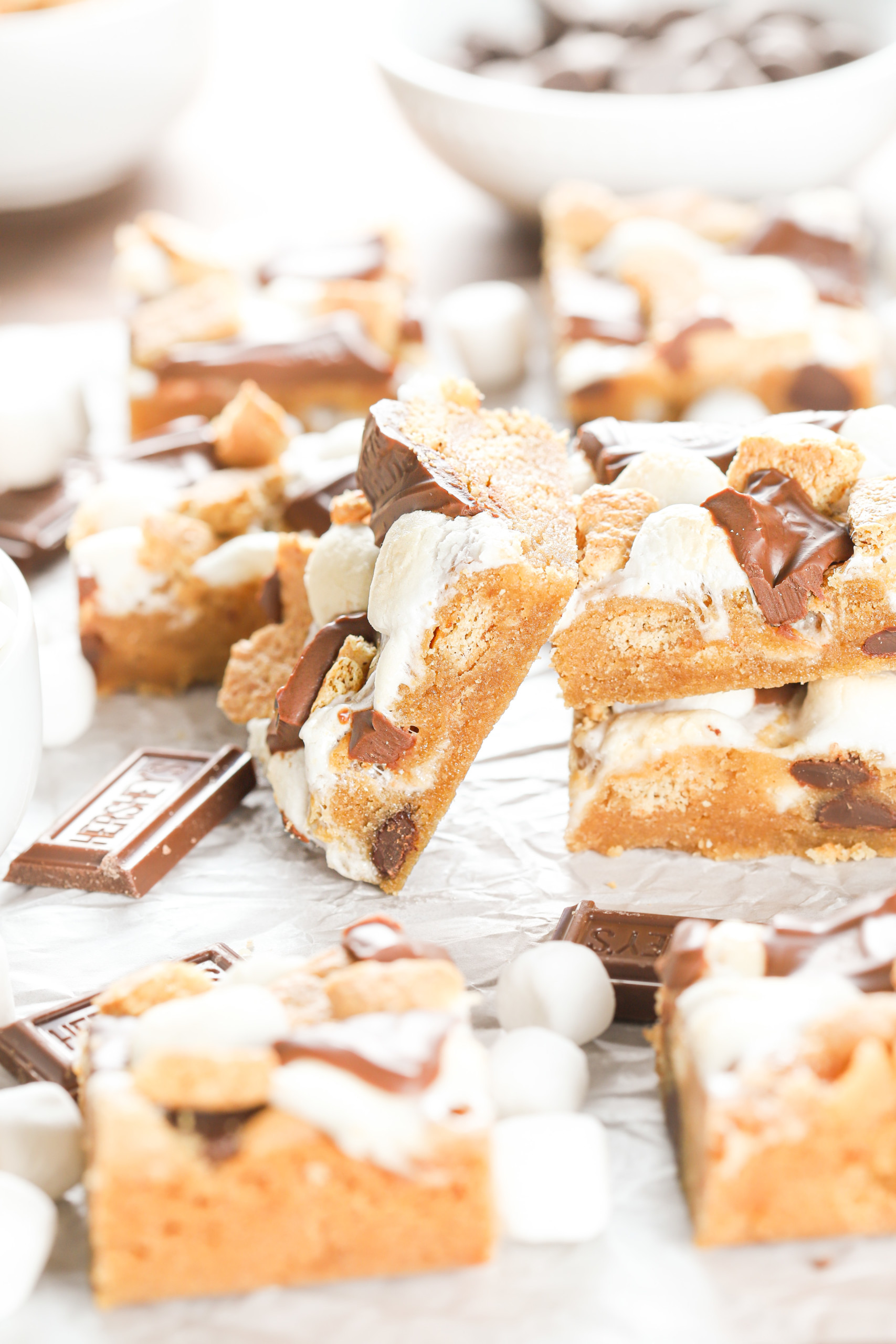 One peanut butter smores bar leaning up against a stack of two bars while surrounded by the remaining batch of smores bars.