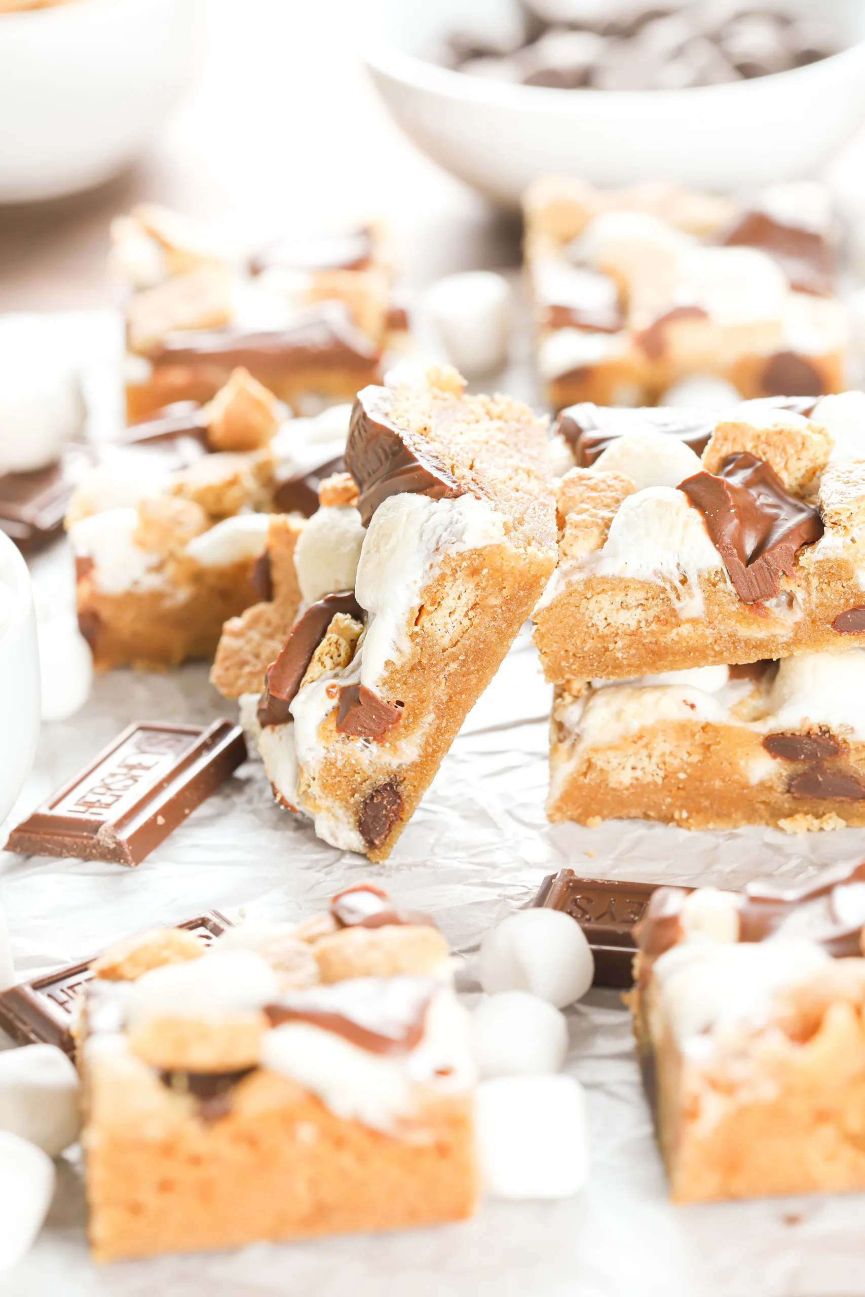 One peanut butter smores bar leaning up against a stack of two bars while surrounded by the remaining batch of smores bars.