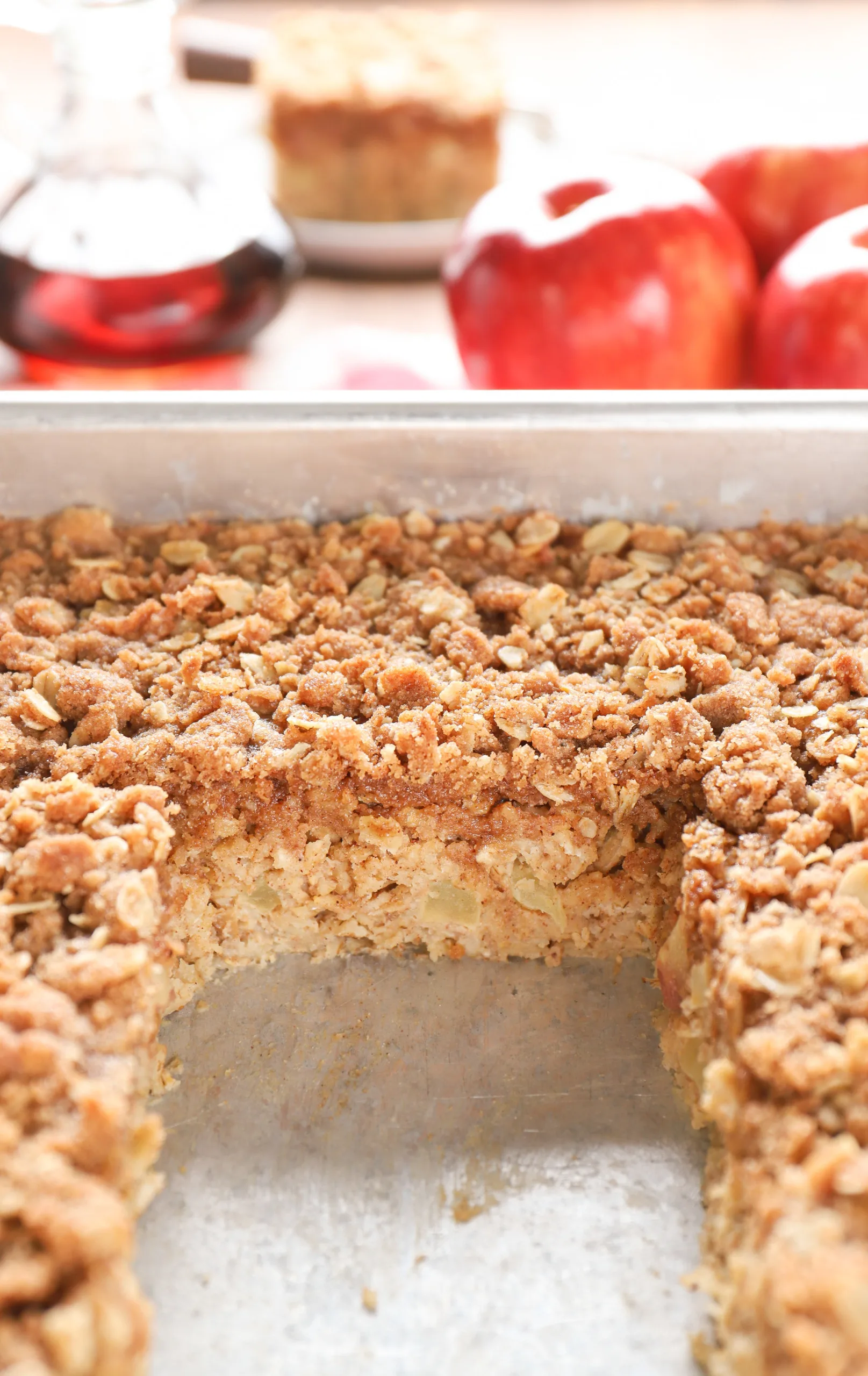 Up close view of the pan of baked oatmeal with a piece missing showing the apples in the filling and the streusel topping.
