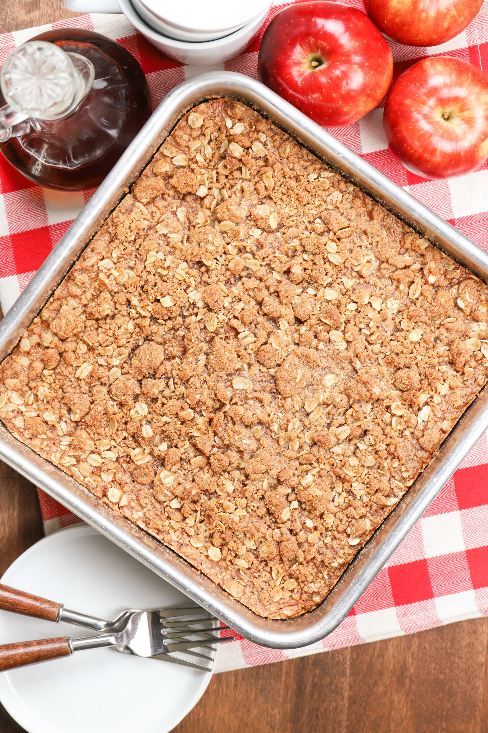 Overhead view of a pan of apple streusel baked oatmeal right out of the oven on a red checked towel.