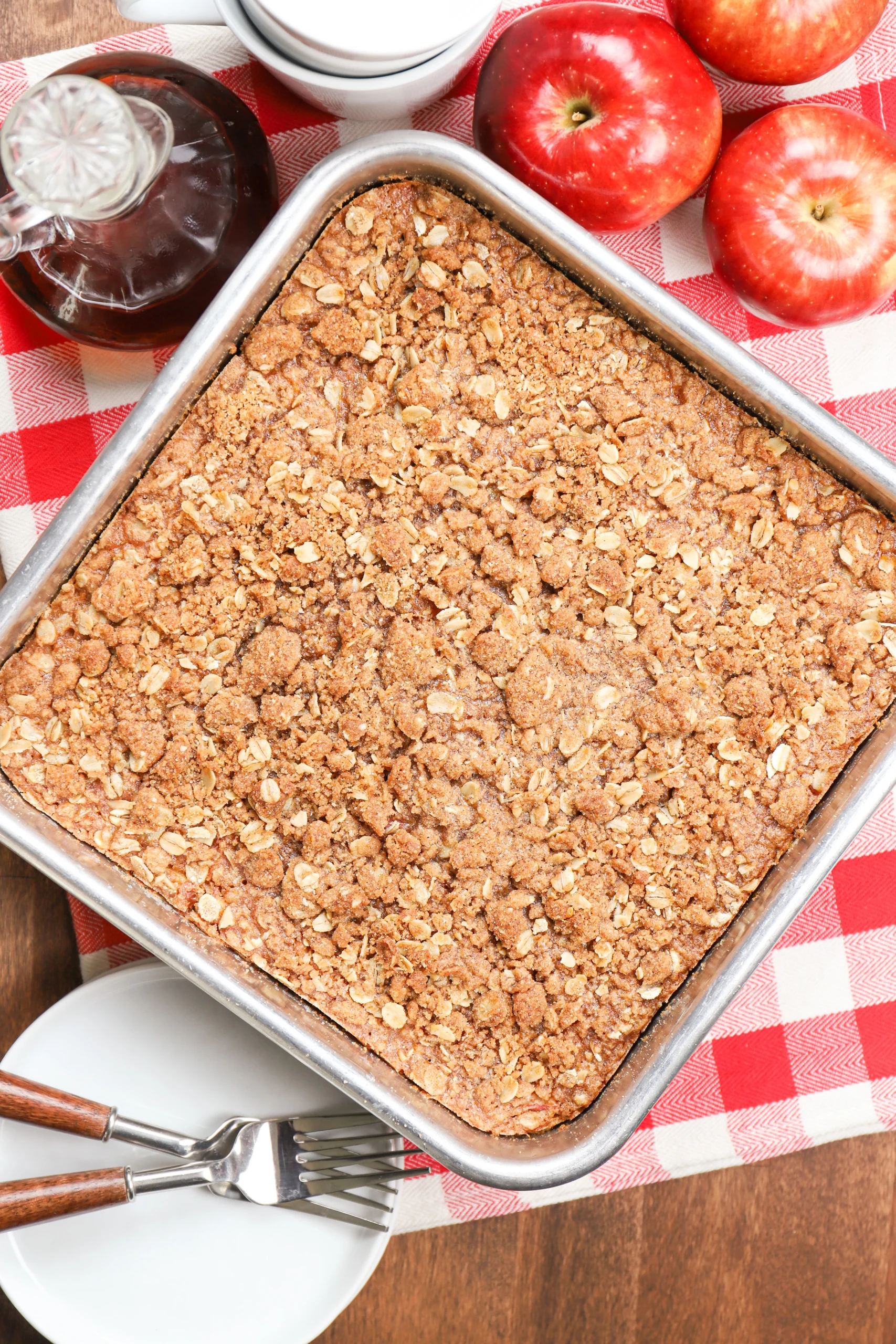 Overhead view of a pan of apple streusel baked oatmeal right out of the oven on a red checked towel.